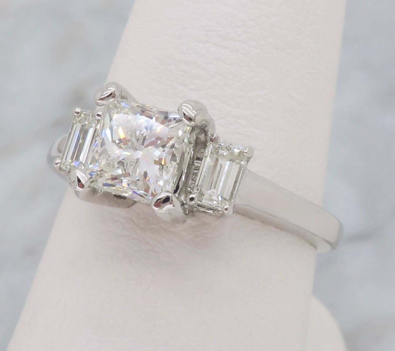 Classic three stone diamond engagement ring featuring a center Princess cut diamonds, flanked by two Emerald cut diamonds. 

Center Diamond Carat Weight: Approximately .90CT
Diamond Cut: Princess Cut
Total Diamond Carat Weight: Approximately