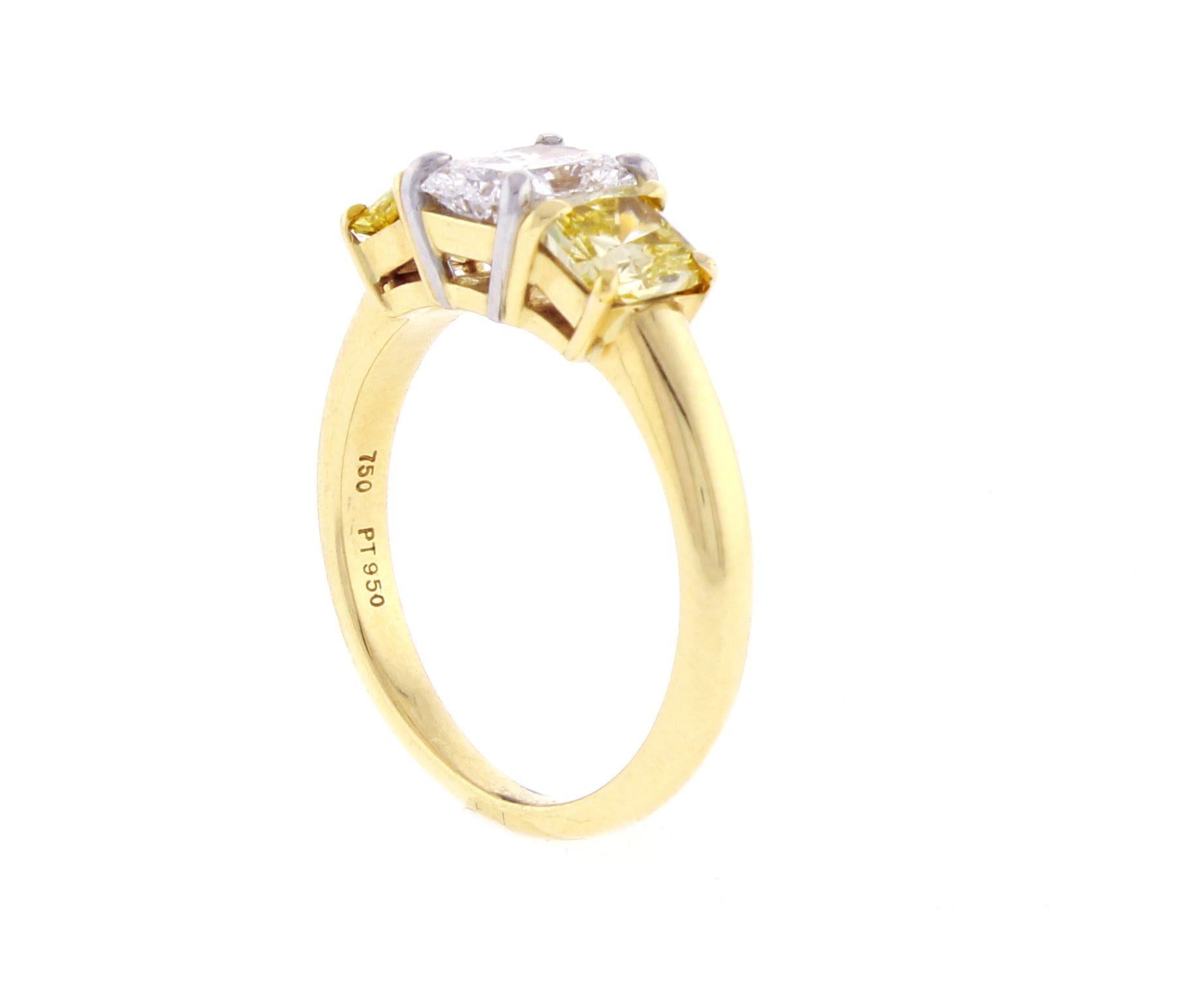 Il diamante centrale di questo anello con tre pietre radianti bianche e gialle ha un peso di .70ct D-VVs1, confermato da GIA #8337858. I due diamanti radianti gialli che li affiancano hanno un peso totale di 0,85 carati. La fascia è realizzata in