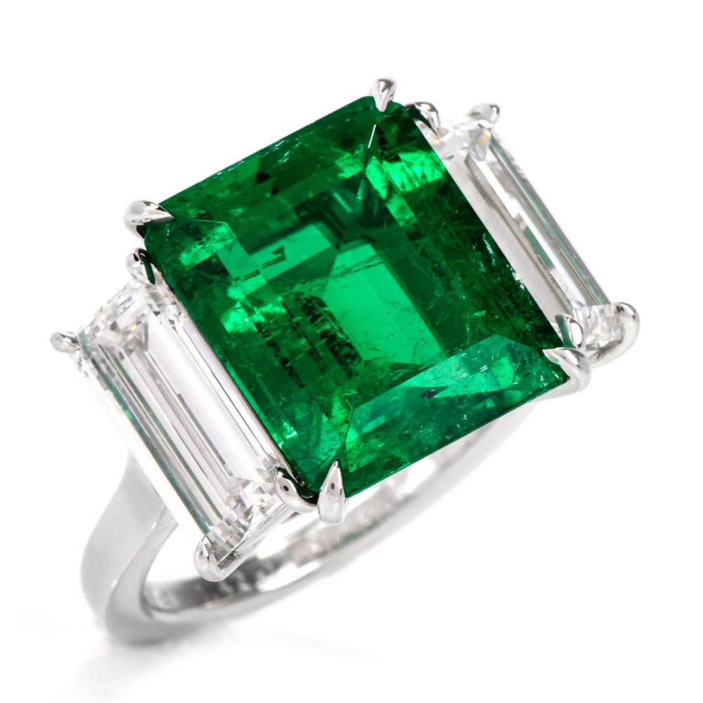 This stunning three stone emerald and diamond ring is crafted in solid platinum. Showcasing a prominent high quality genuine rectangular emerald-cut Colombian emerald approx. 6.70 carats with no treatments, except minor oil and measuring 13.00 x