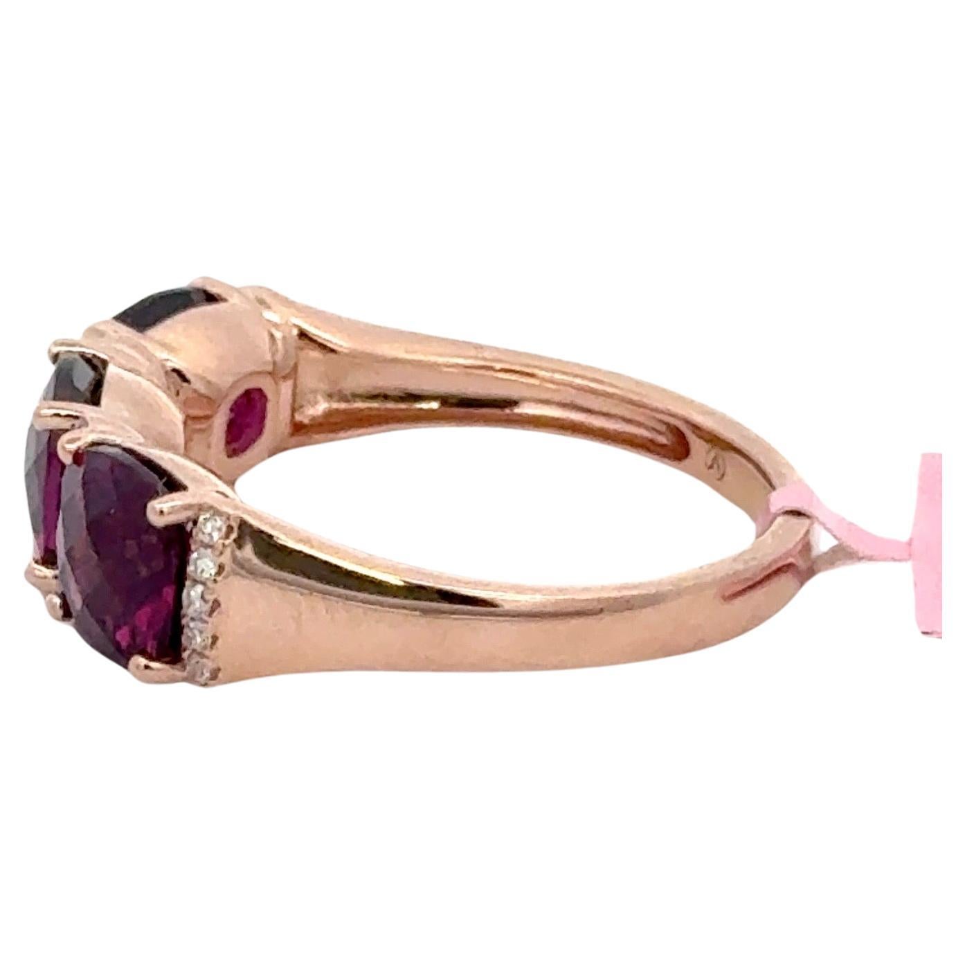 Bague en or jaune 14 carats comprenant trois rhodolites à facettes de taille coussin pesant 3,94 carats flanquées de 20 brillants ronds pesant 0,09 carats.