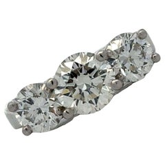 Platin-Ehering mit drei Steinen im runden Brillantschliff und Diamant