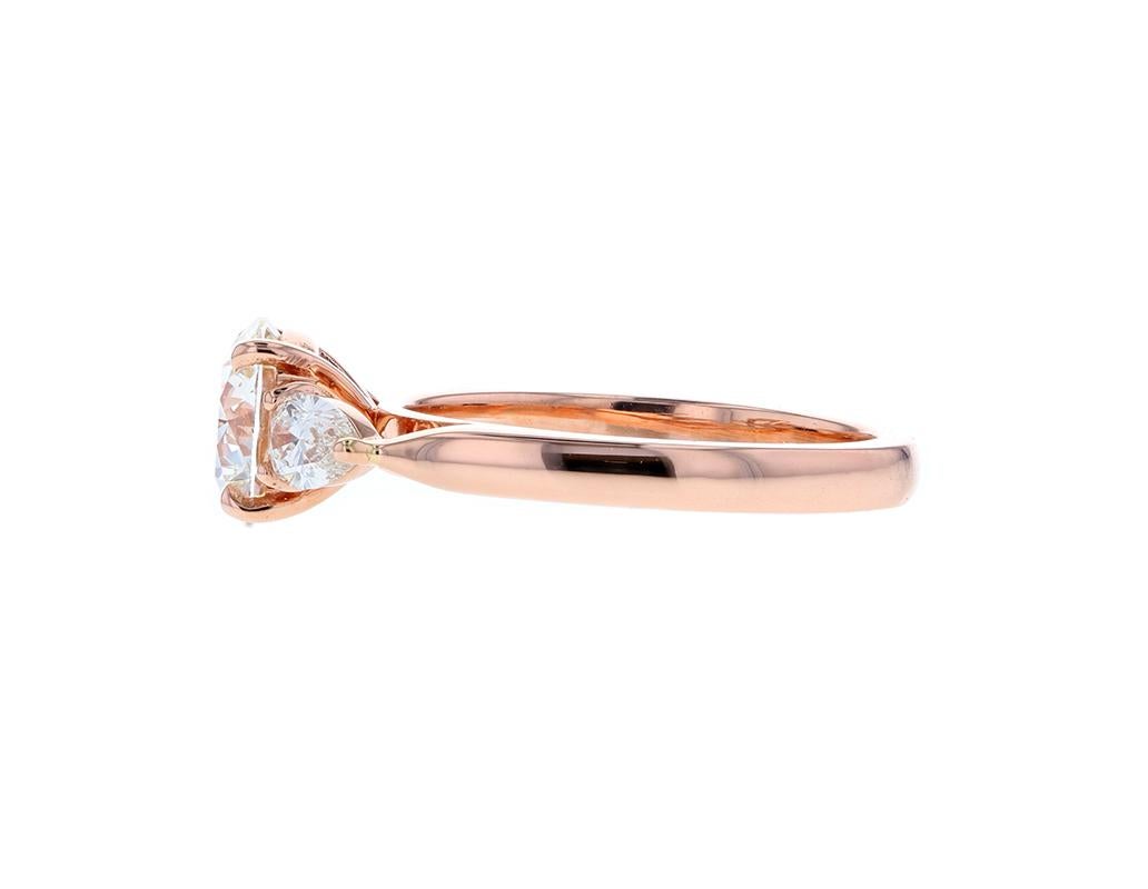 A Three Stone Round Diamond Engagement Ring with Pear Shaped Side Stones in Rose Gold and a slightly raised profile creates the perfect ring. Featuring a round center diamond and two perfectly cut pear shaped side stones to match the center in color