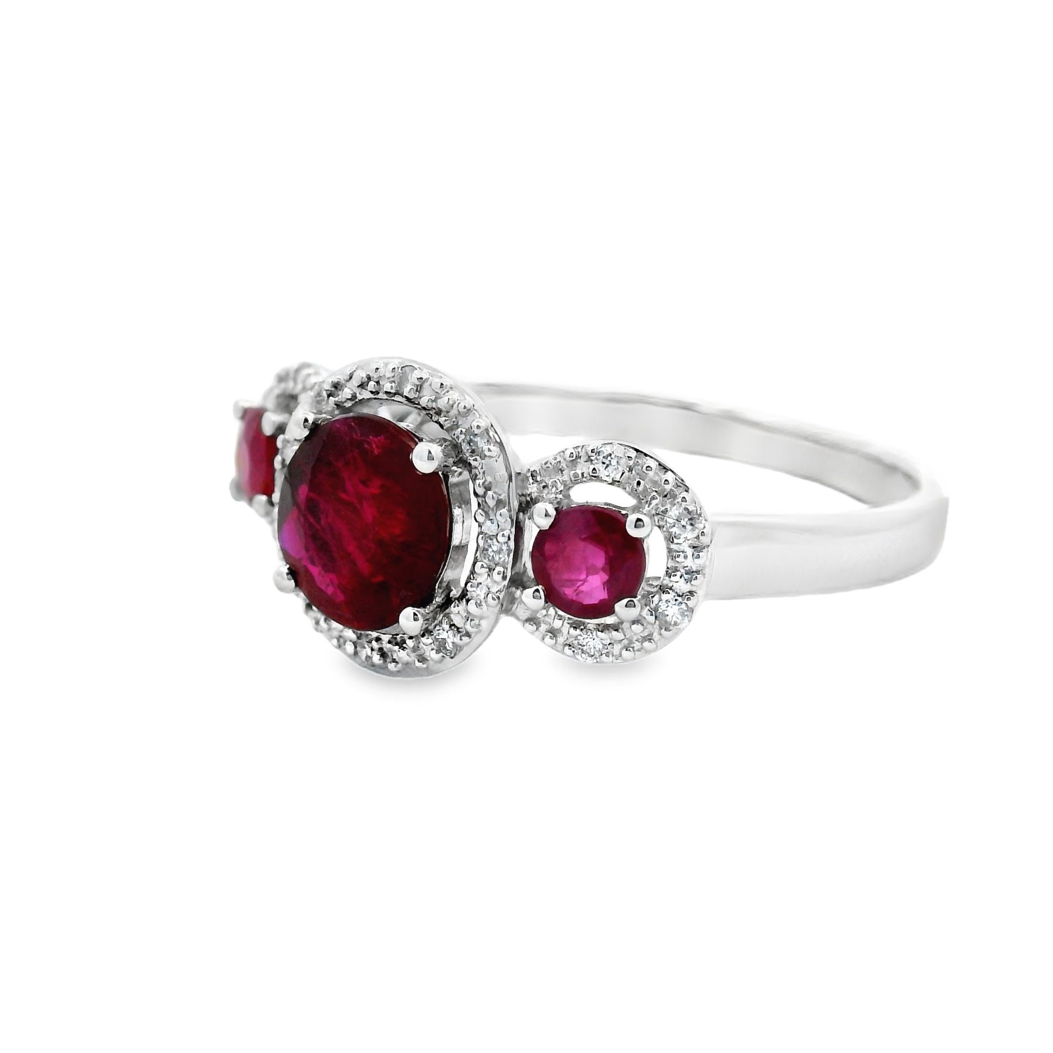 This elegant three-stone ring showcases a vibrant trio of round natural rubies set in 14K white gold, with a total ruby weight of 1.15 carats. The centerpiece is a 6mm ruby weighing approximately 0.85 carats, flanked by two 3mm rubies totaling 0.30