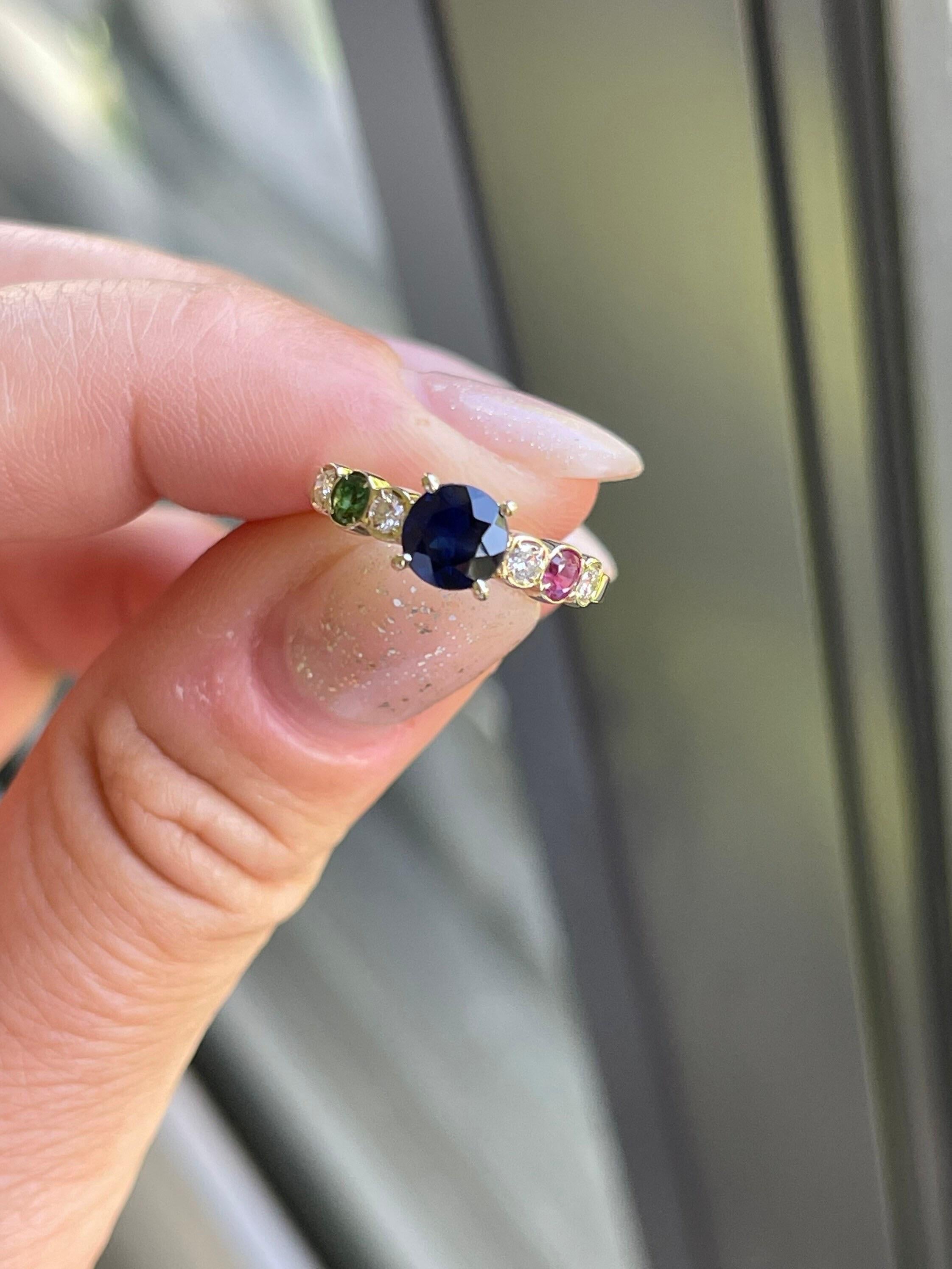 1ct Zentrum blauer Saphir begleitet von Diamanten, einzelne Rubin und einzelne Smaragd in 18KT Gelbgold. Die Edelsteine sind von guter bis mittlerer Qualität mit einigen kleinen, mit bloßem Auge erkennbaren Einschlüssen. Dies ist normal, wie Rubine