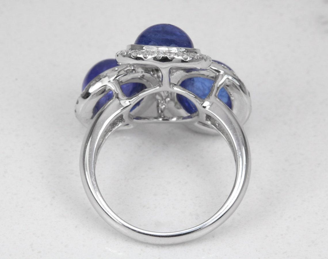 Elegamment présentée, cette magnifique bague à trois pierres en tanzanite et diamant est destinée à un anniversaire ou à une bague pour la main droite. Cette bague de cocktail unique en son genre est captivante sous tous les angles. Trois