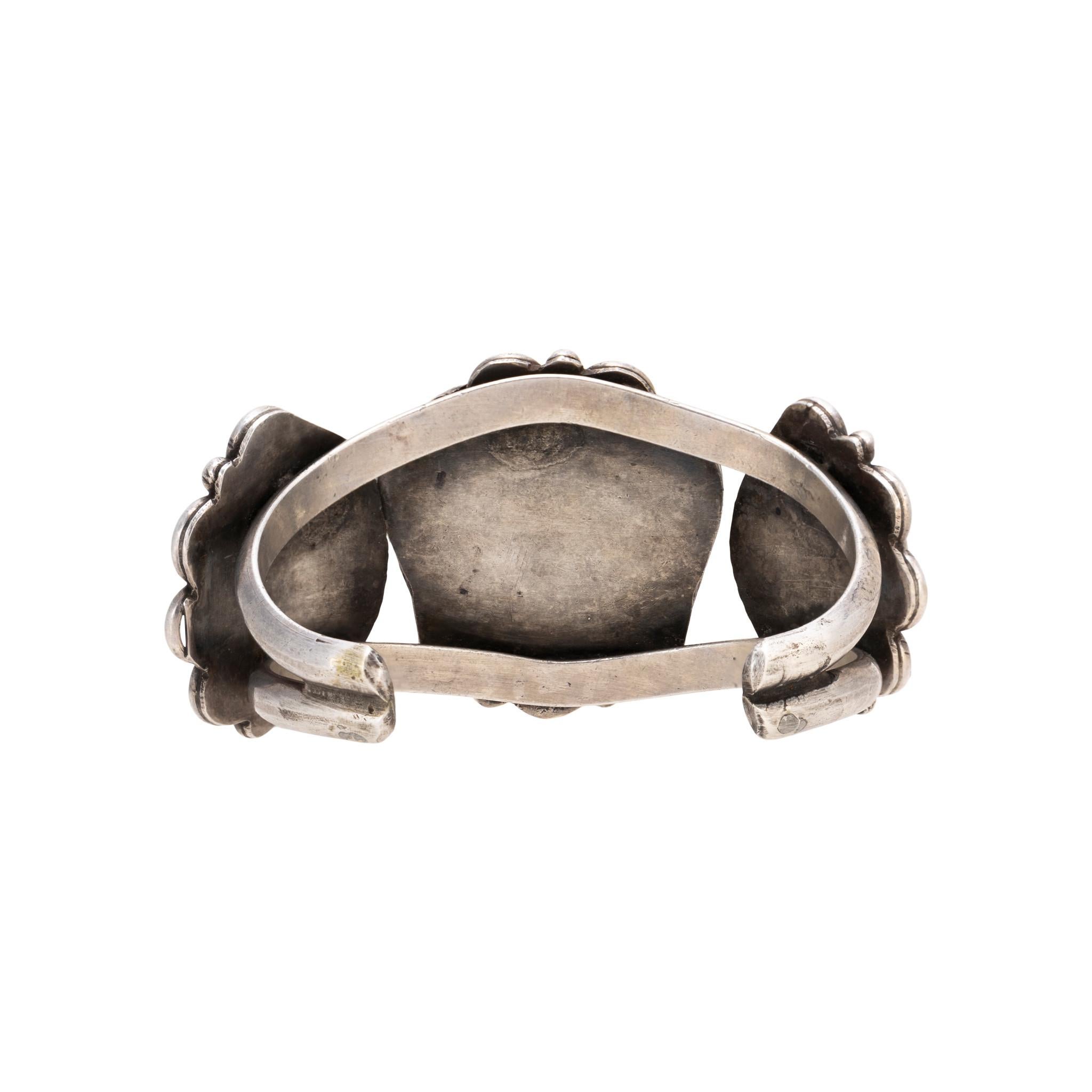 Pulsera brazalete de plata de ley con tres excepcionales piedras de turquesa de montaña. Las piedras están engastadas en una caja de sombra con festón, abalorio de plata de ley, pluma y borde de cuerda retorcida. La turquesa es de un azul intenso