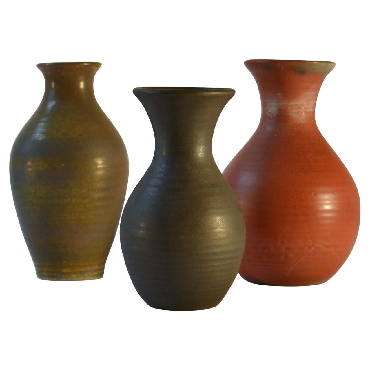 Tres jarrones de Studio Pottery en rojo coral, negro mate y verde musgo, creados en el torno por ceramistas holandeses de gran habilidad técnica en la década de 1960, fabricados por De Olde Kuyk (DOK) Milsbeek, Países Bajos. Los esmaltes de colores