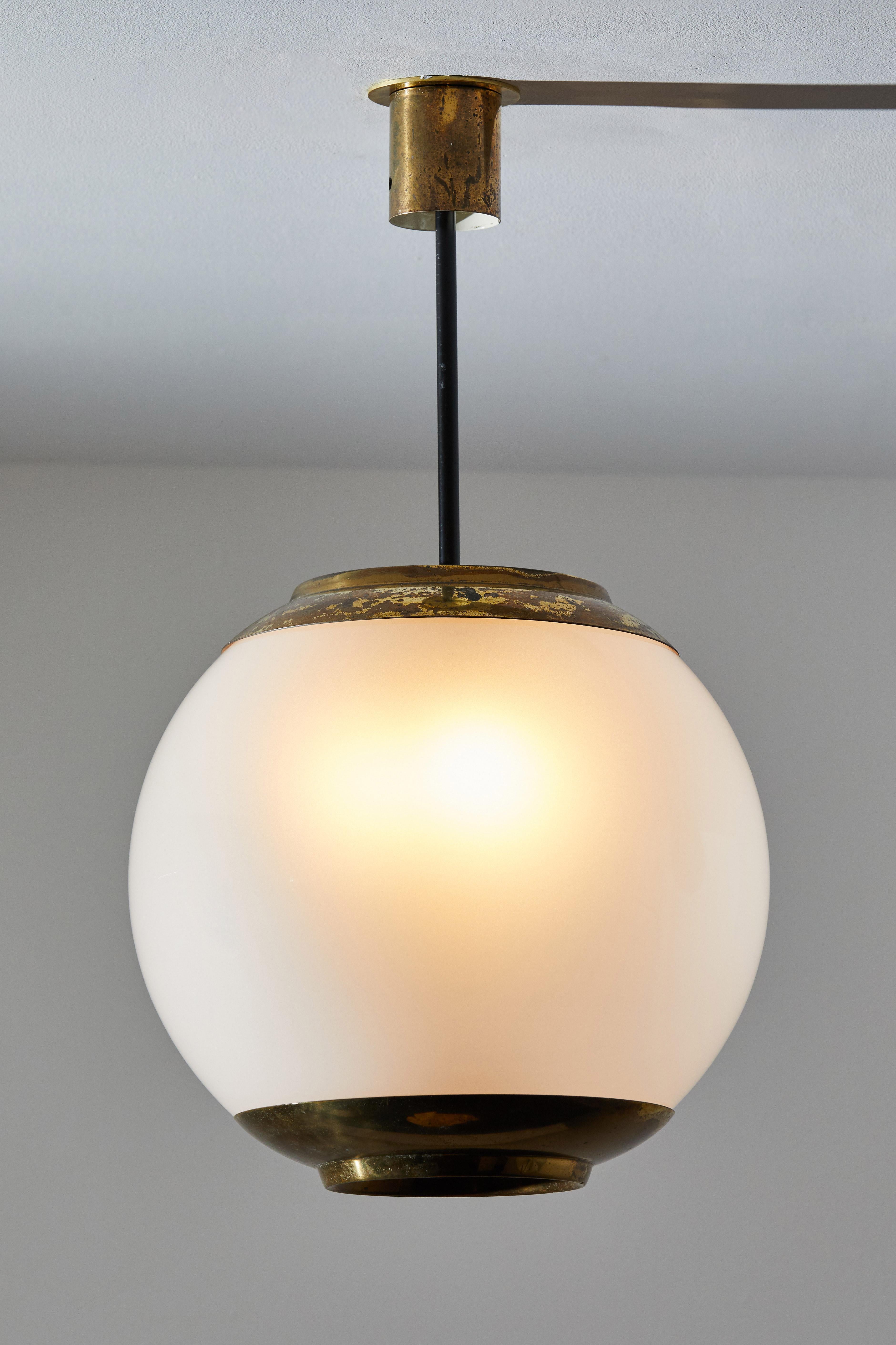 Three suspension lights by Caccia Dominioni for Azucena. Designed and manufactured in Italy, circa 1950s. Opaline glass, brass. Rewired for U.S. junction boxes. Original canopy, custom brass ceiling plate. Each light takes one E27 100w maximum bulb.