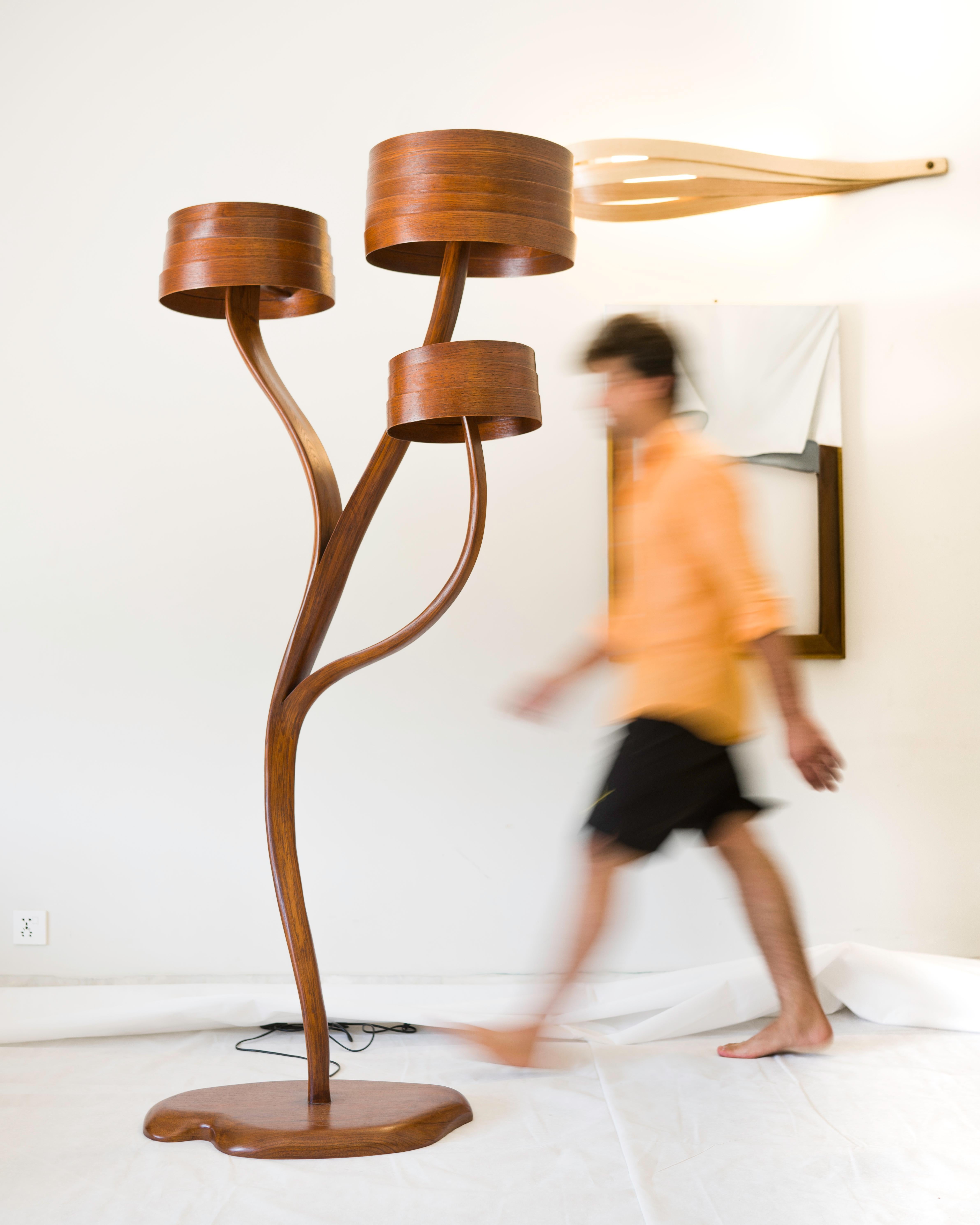 A lighting piece crafted by hand; the piece stems from the base and flows to have three lighting sources, at different levels. All of the lamp shades are different from the other in size; which illuminate the piece and the space around it in a