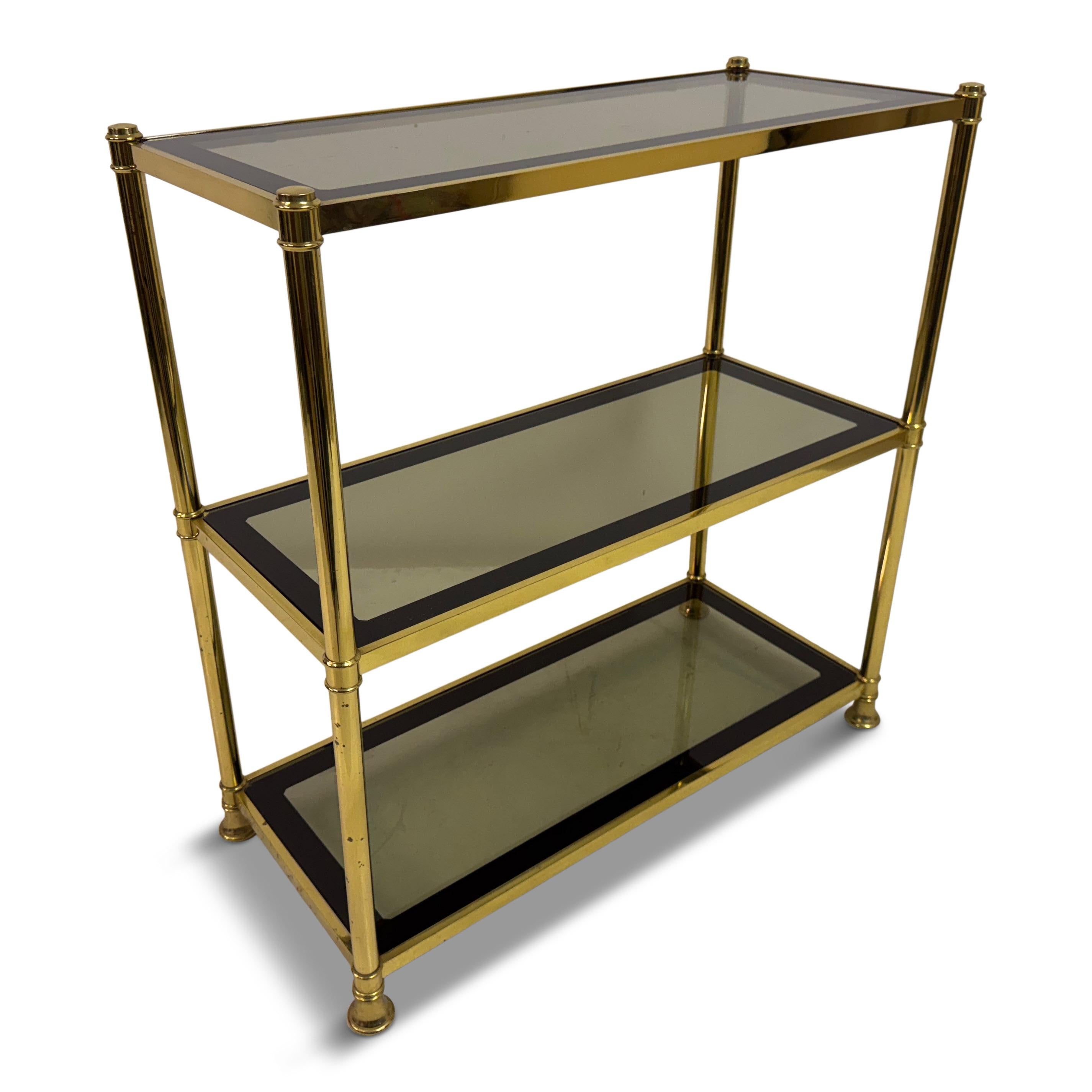 Étagère à trois niveaux en laiton et verre fumé, 1970

Étagère à trois niveaux en laiton poli avec étagères en verre fumé, datant des années 1970. Le cadre est formé de minces supports en laiton avec des détails tournés et de petits pieds boules,