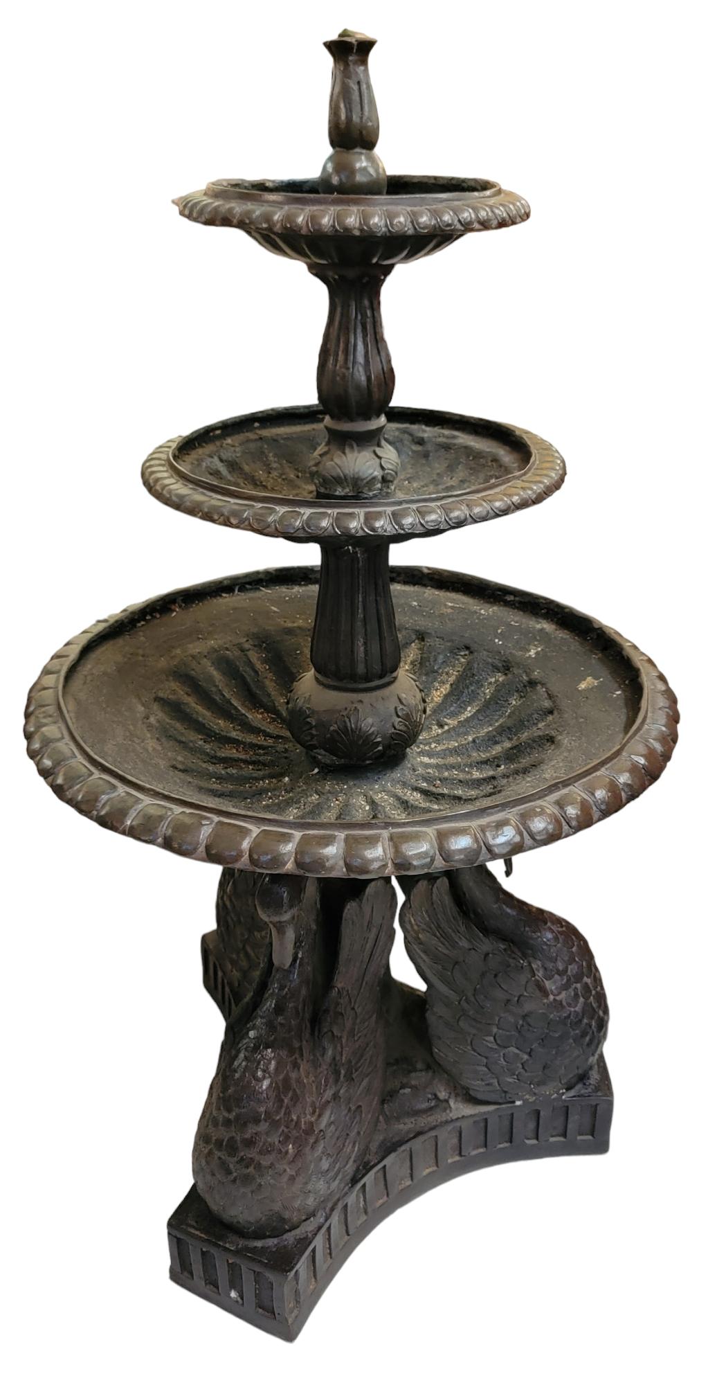 Three tier Bronze fountain with swan base. The swans have their neck bent downward in a docile and strong at the same time. Water is shot out of the top and waterfall effects its way down. wonderful patina and great look.
