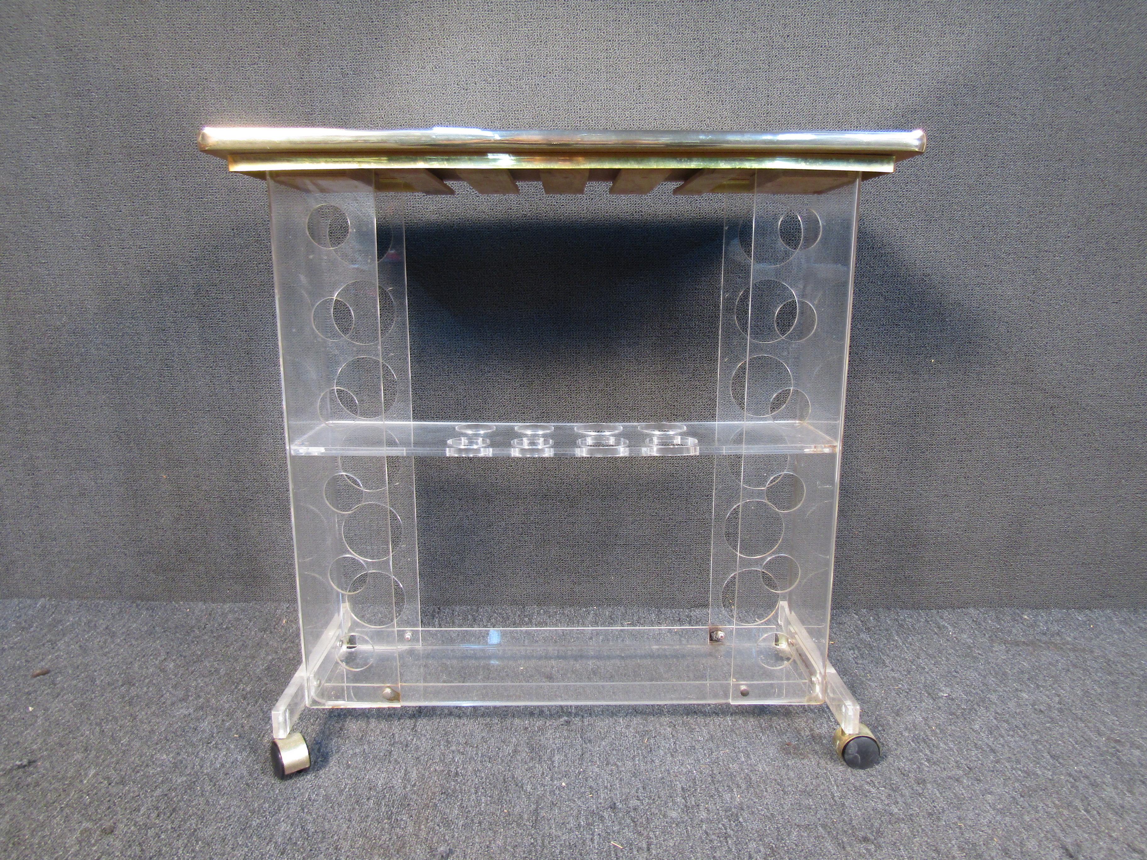 This vintage bar cart combines a lucite frame with metal accents and a mirrored top for a beautiful Mid-Century Modern look. Three tiers allow for a generous amount of storage along with circular cut-outs on the lucite that allow for storage of