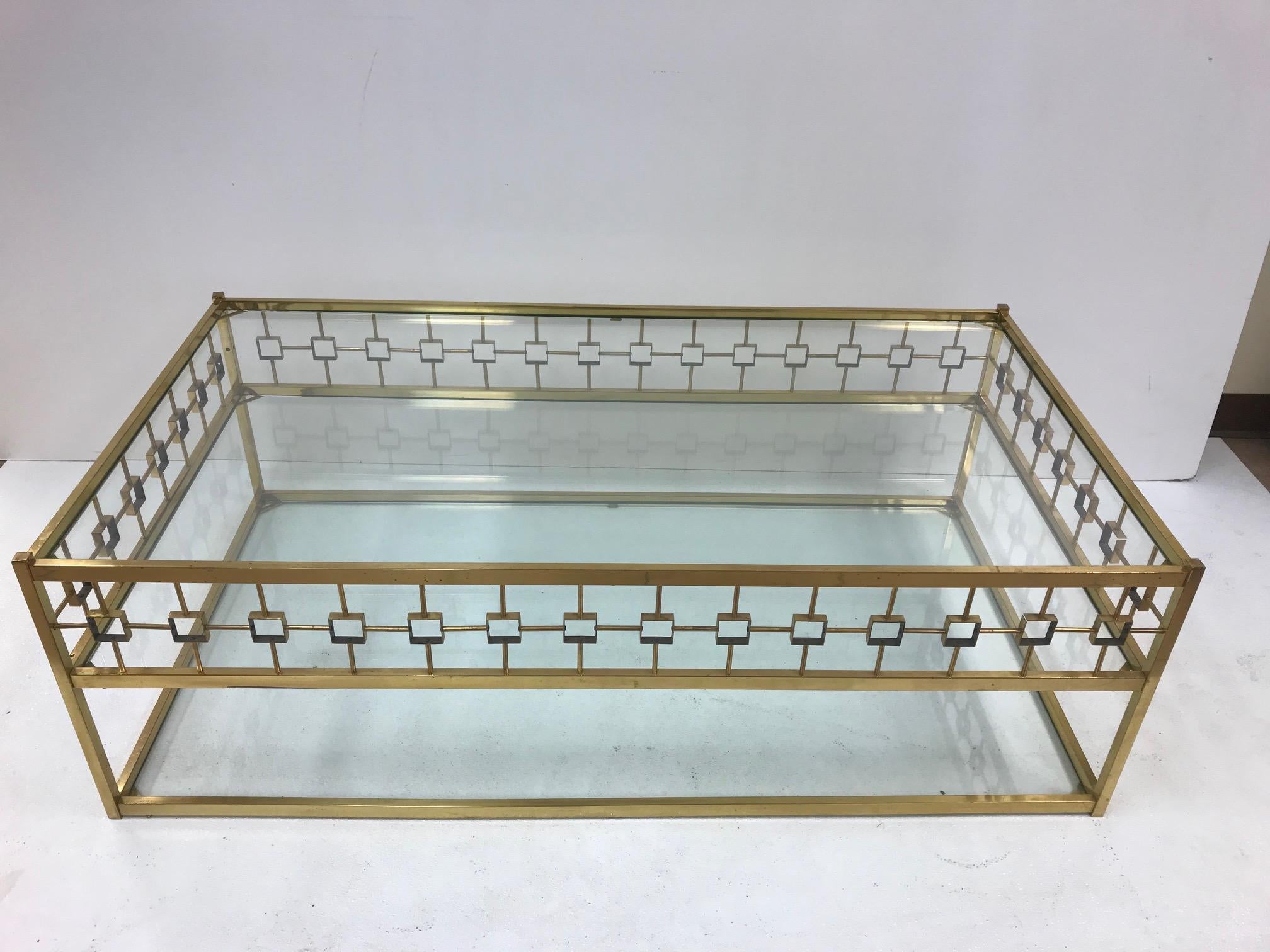 Table basse à trois niveaux en laiton et verre de style Maison Jansen. La table est ornée d'une garniture décorative et de trois niveaux de plateaux en verre.