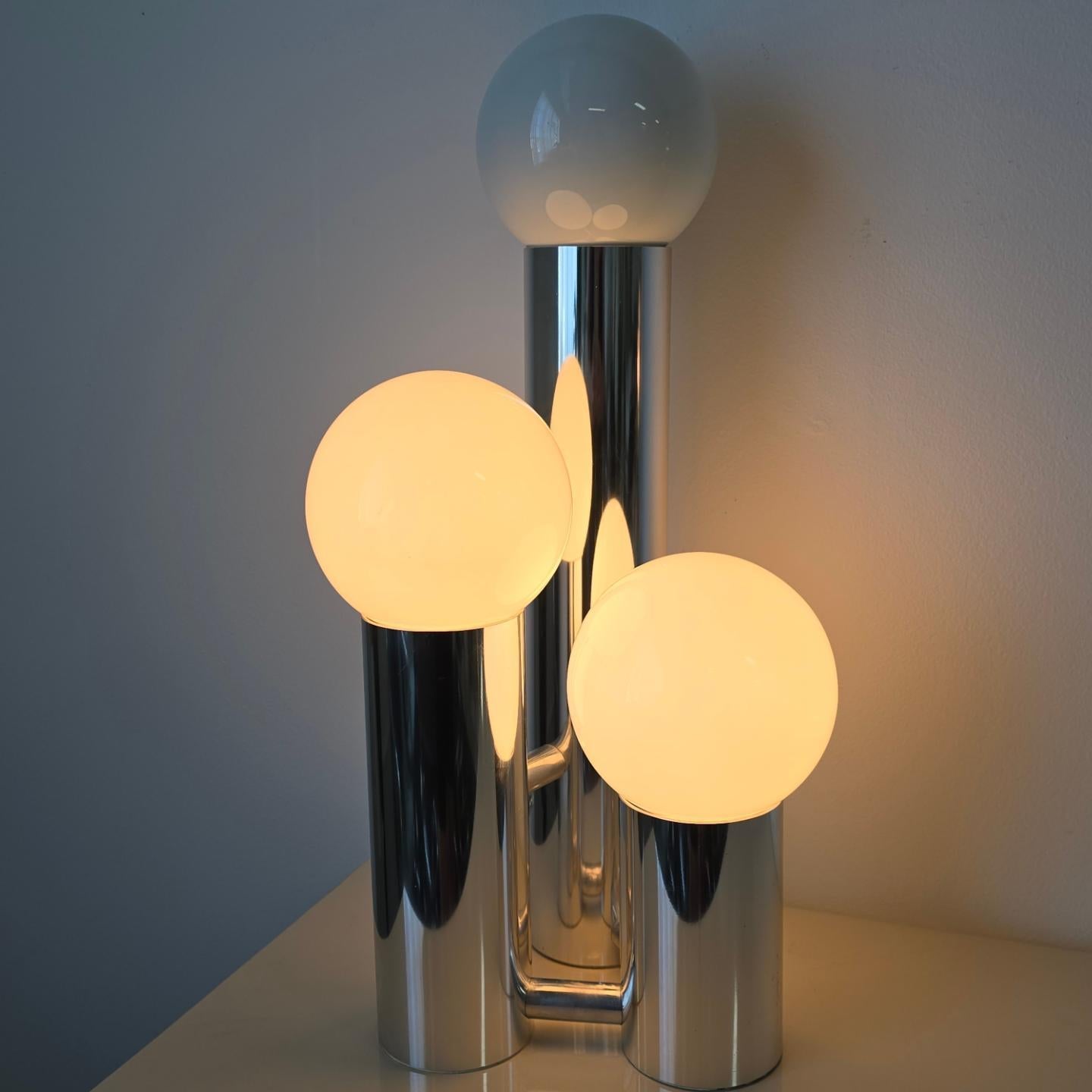 Three tier tubular chrome table lamp from the 1970s. This table lamp features three tiers in varying heights. It has three mode switch which lights the bottom bulbs, top bulbs, and all three. This chrome table lamp would compliment any style of home