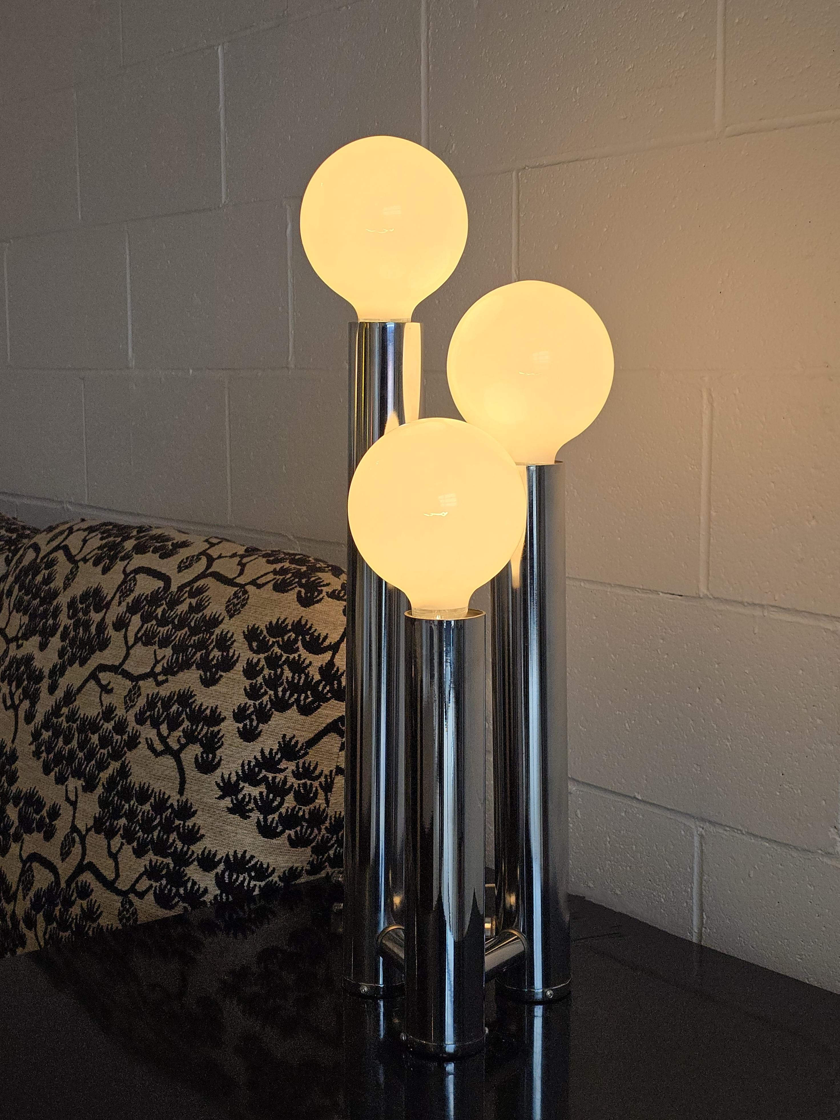Three tier tubular chrome table lamp from the 1970s. This table lamp features three tiers in varying heights. The chrome base holds three G40 bulbs and has three mode switch which lights the bottom bulb, top bulbs, and all three. This chrome table