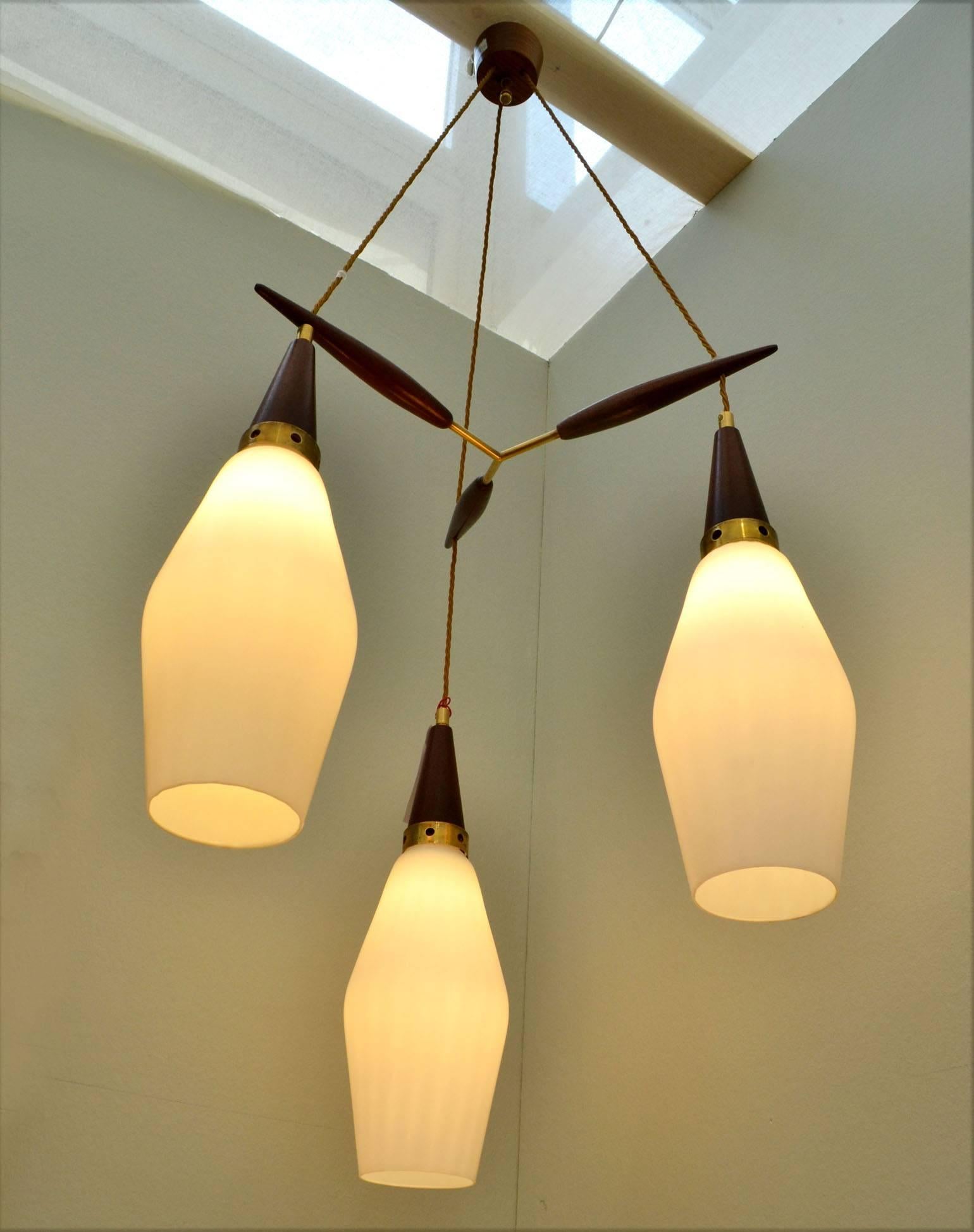 The three pendants are in dark teak wood, brass and opaline glass shades spaced by a teak and brass suspension and connected to a teak ceiling rose.
Dimensions of each pendant:
Height 40 cm,
diameter 19 cm.
Each shade assembly can be adjusted in