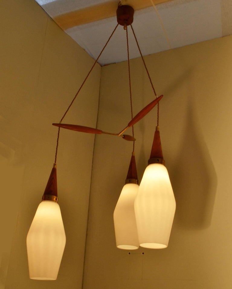 The three pendants are in teak, brass and opaline glass shades spaced by a teak and brass suspension and connected to a teak ceiling rose.
Dimensions of each pendant:
Height 40 cm.
Diameter 19 cm.
Each shade assembly can be adjusted in height so