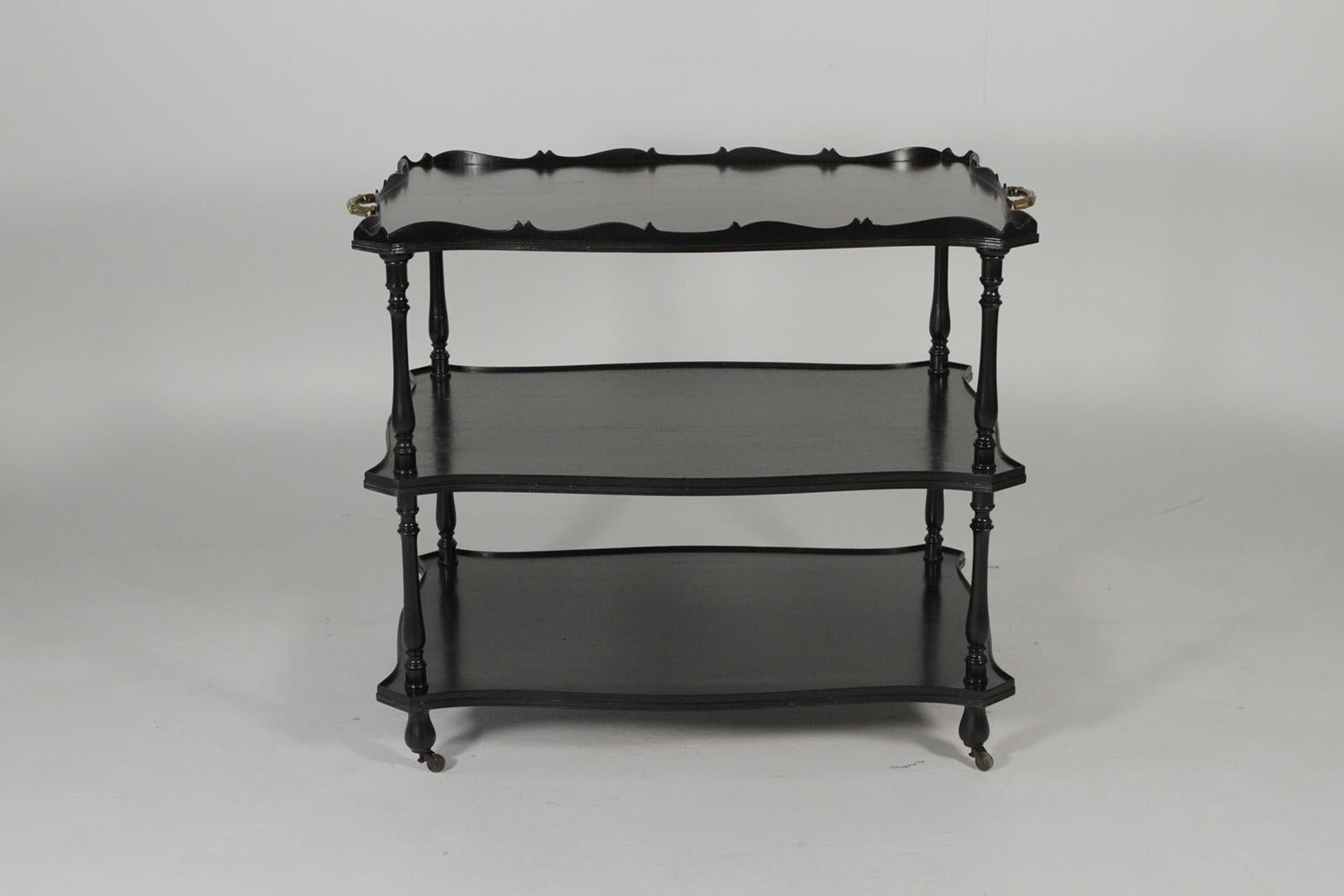 Three-tiered ebonized beverage dessert cart with cast bronze handles in the manner of Maison Jansen. The large cart with three shelves the top with a scalloped gallery edge. The front and back with high quality cast gilt bronze handles.