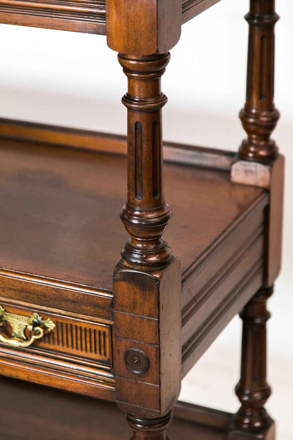 This shelf/server has a heavily carved broken arch crestrail with a center scallop shell carved in high relief which is flanked by carved leaf arabesques and a carved wave scroll. The three shelves have carved and applied moldings. The top and lower