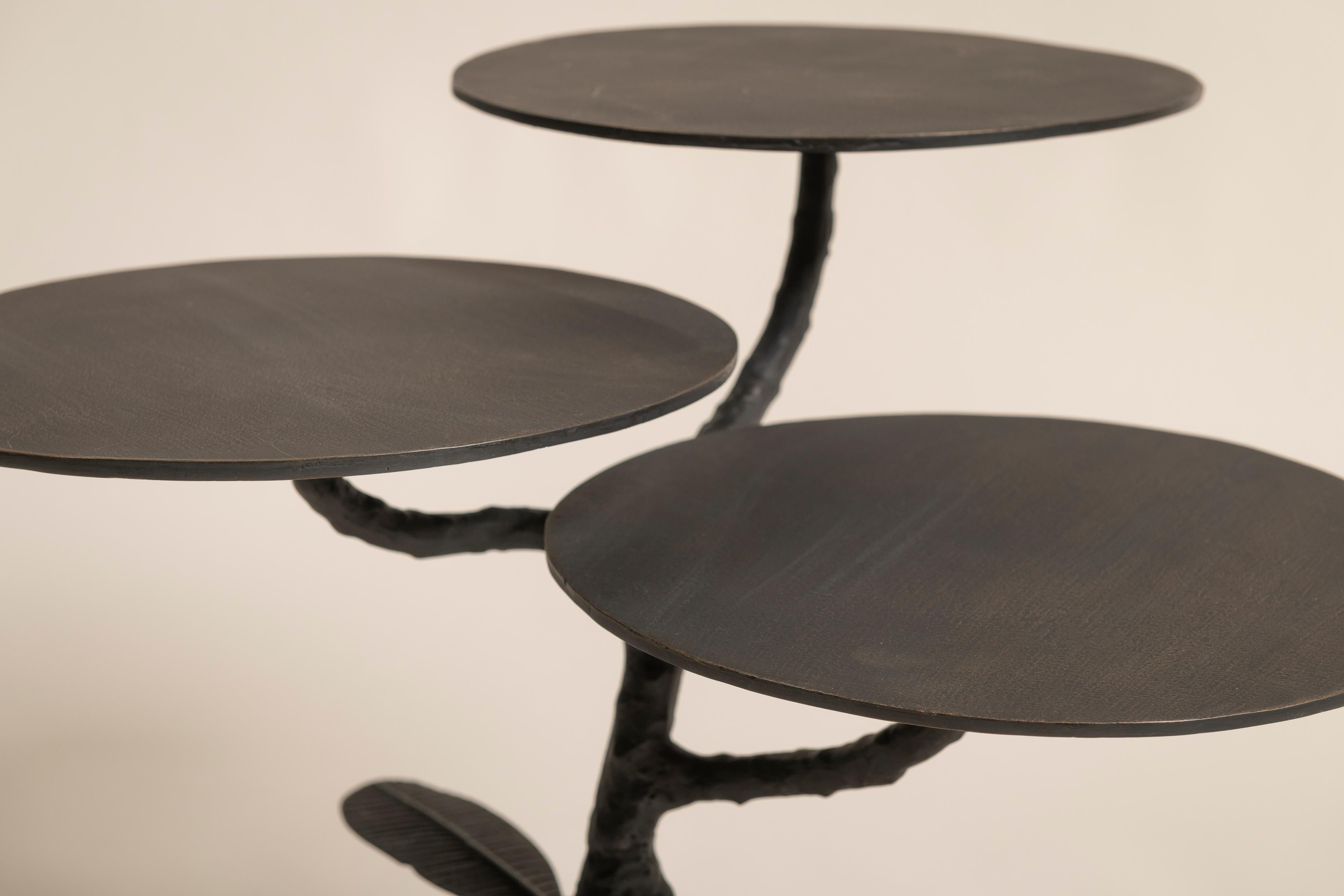 Stunning three-tiered iron Ulta Champa table from the Botanical Tables Collection by Stephanie Odegard. Handcrafted in India using traditional sand-casting techniques, this exquisite piece is inspired by the Frangipani tree, featuring intricately