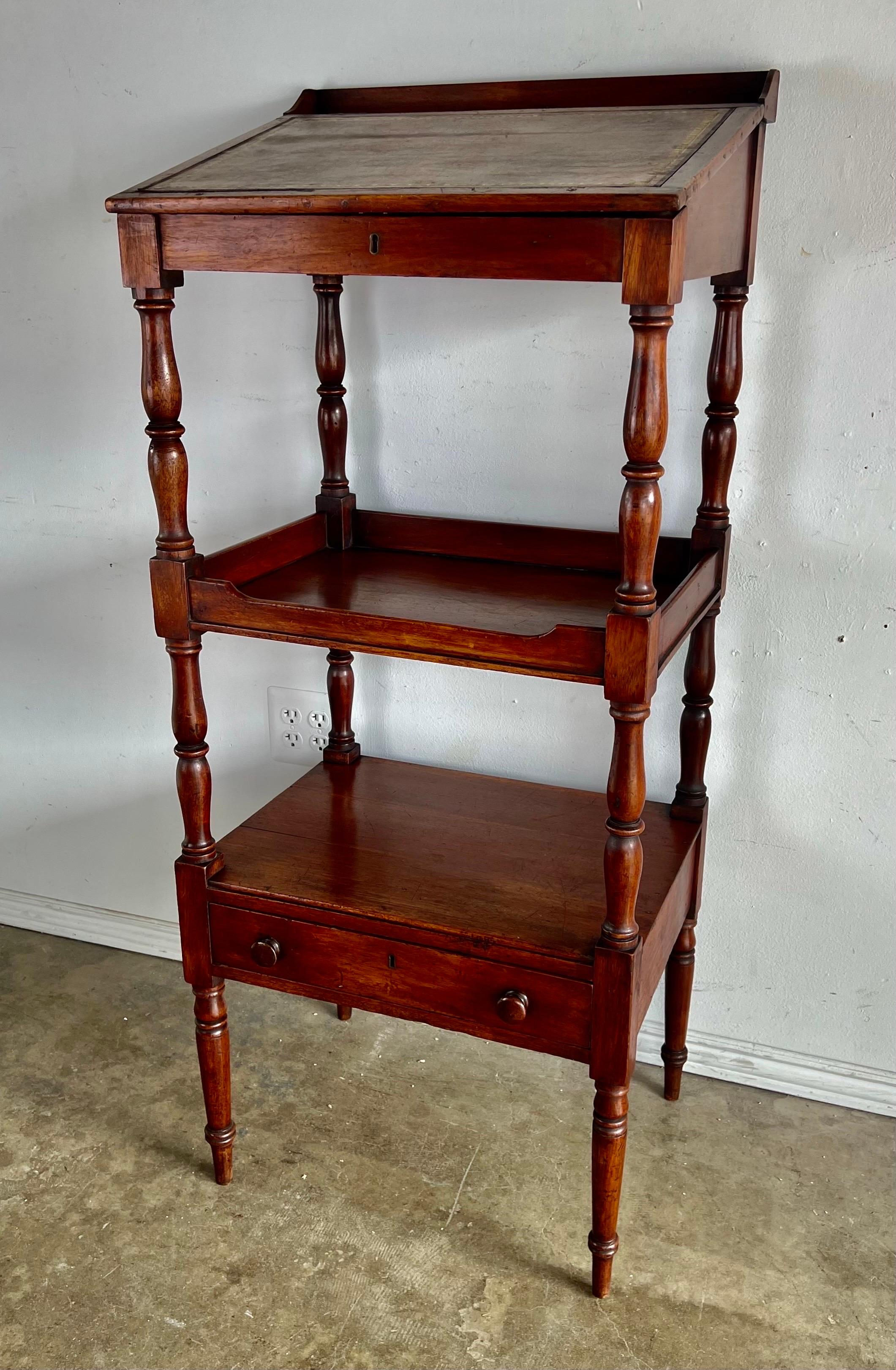 American mahogany three tiered standing lectern The embossed leather top writing surface opens for storage. There is also plenty of space on the shelves below. Single functioning drawer.