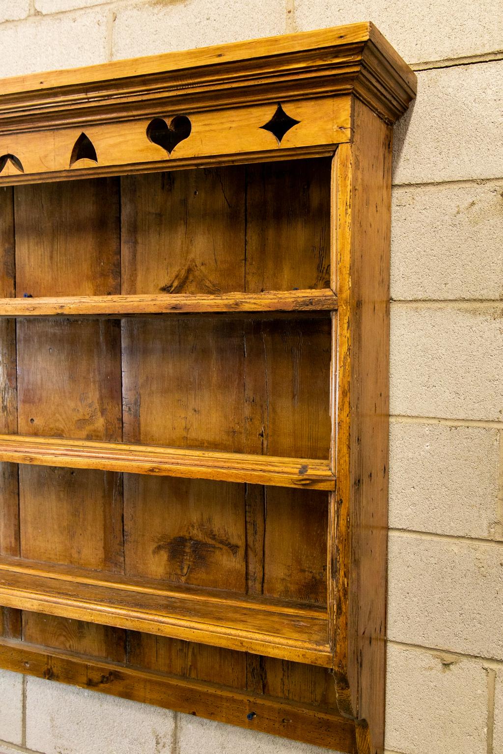 Three-tiered pine hanging shelf, with plate moldings on each shelf, the frieze carved with heart and geometric designs.