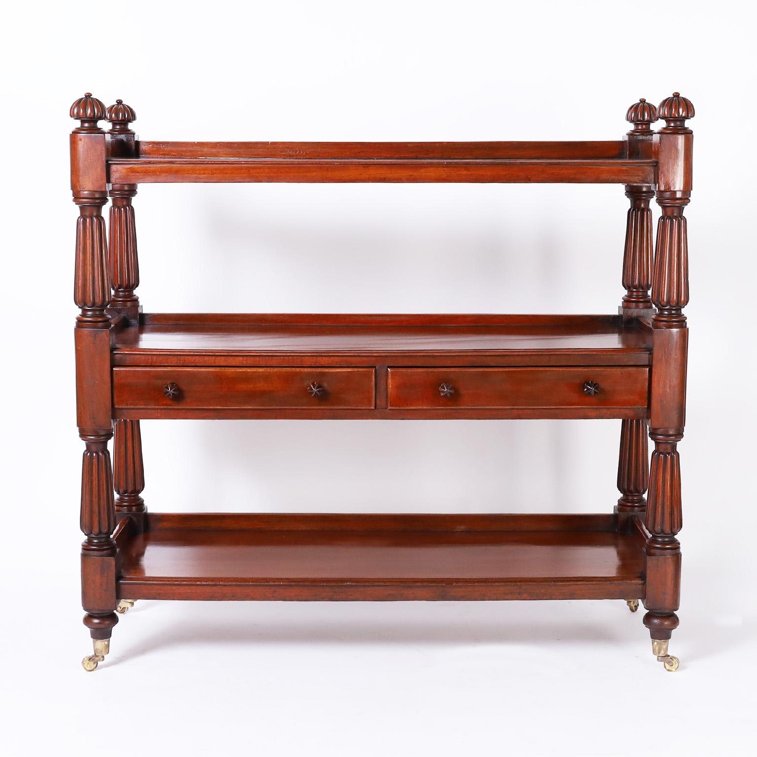 19th century English three tiered server or etagere crafted in well grained mahogany with two drawers in the center, four turned and beaded support columns with matching beaded finials and brass casters.