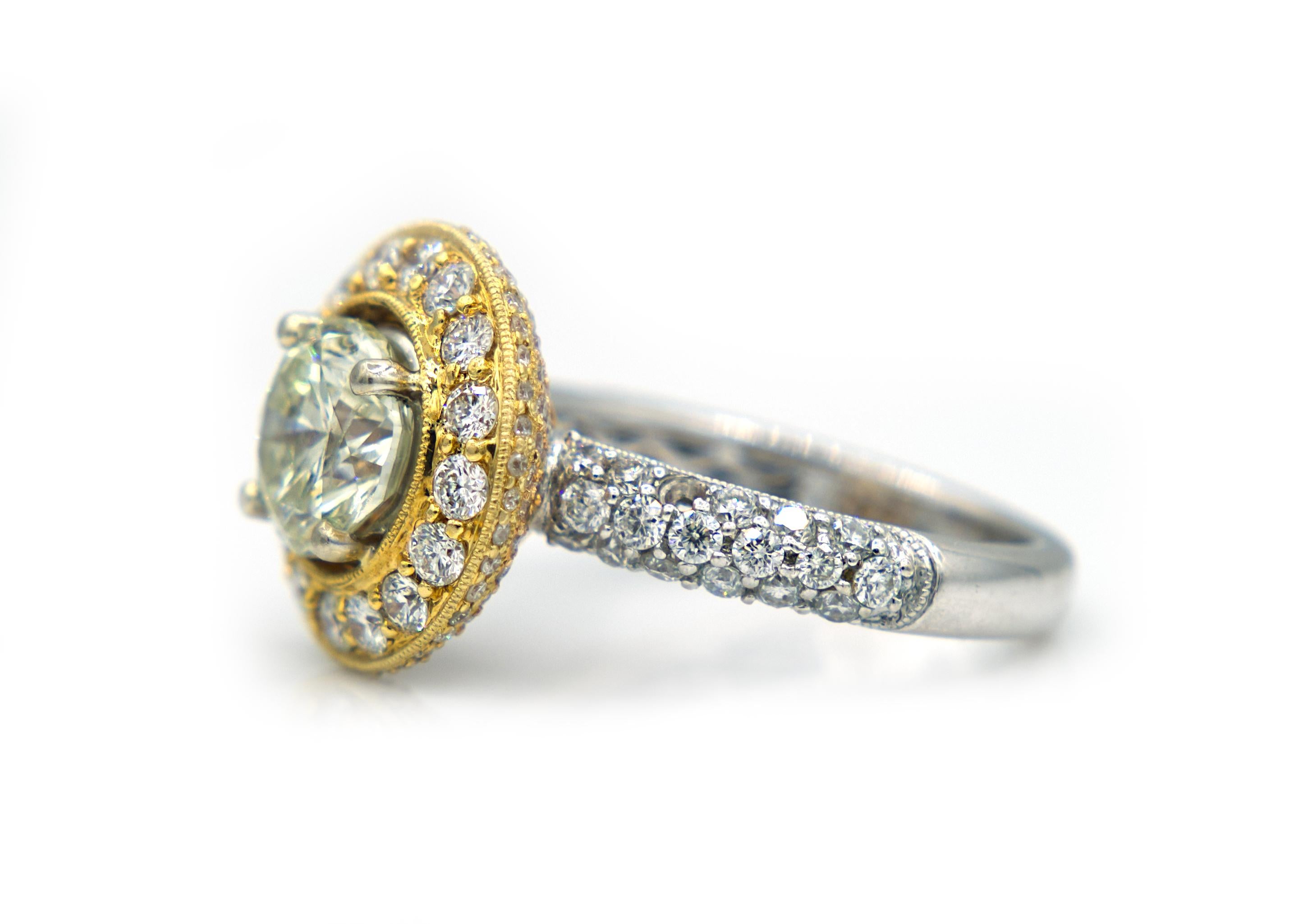 This spectacular ring is made of 18K White, Rose and Yellow Gold. The center Diamond has a light, fancy yellow color and weighs in at 1.80 carats total. It rests on a circular setting, encrusted in round-cut, pave-set Diamonds, with the top face