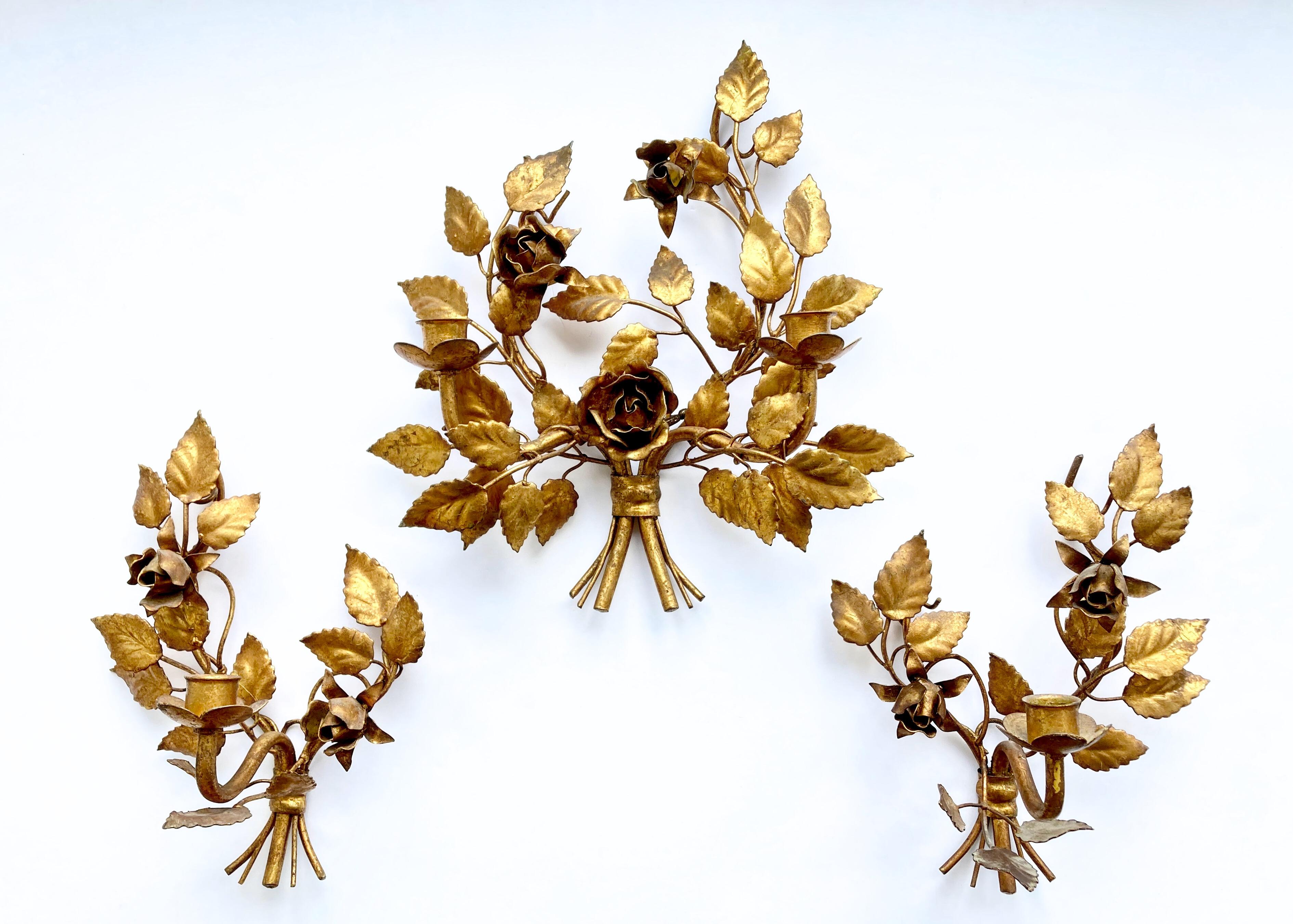 A rare find not to be missed: A set of three matching, very decorative, vintage wall candle sconces in a pure Hollywood Regency style. The set consists of one larger wall sconce with two arms and two smaller ones with single arms. The wall sconces