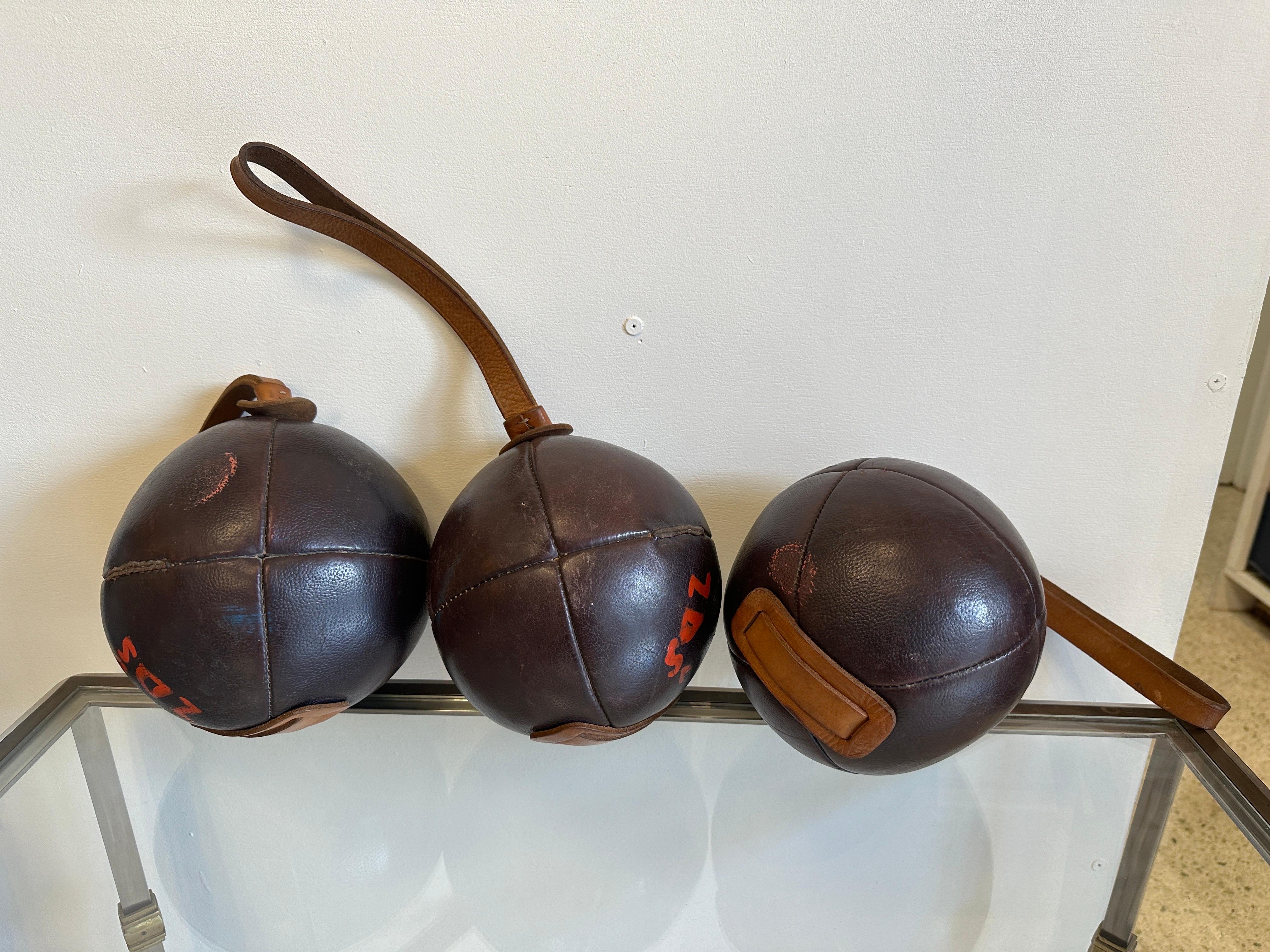 Whimsical leather ball weights (THREE AVAILABLE - sold individually) from France.  Saddle leather ball with strap for lifting. Good vintage condition. Wear to leather. Cool object for a home gym or office.

NOTE: Length from the top of the strap to