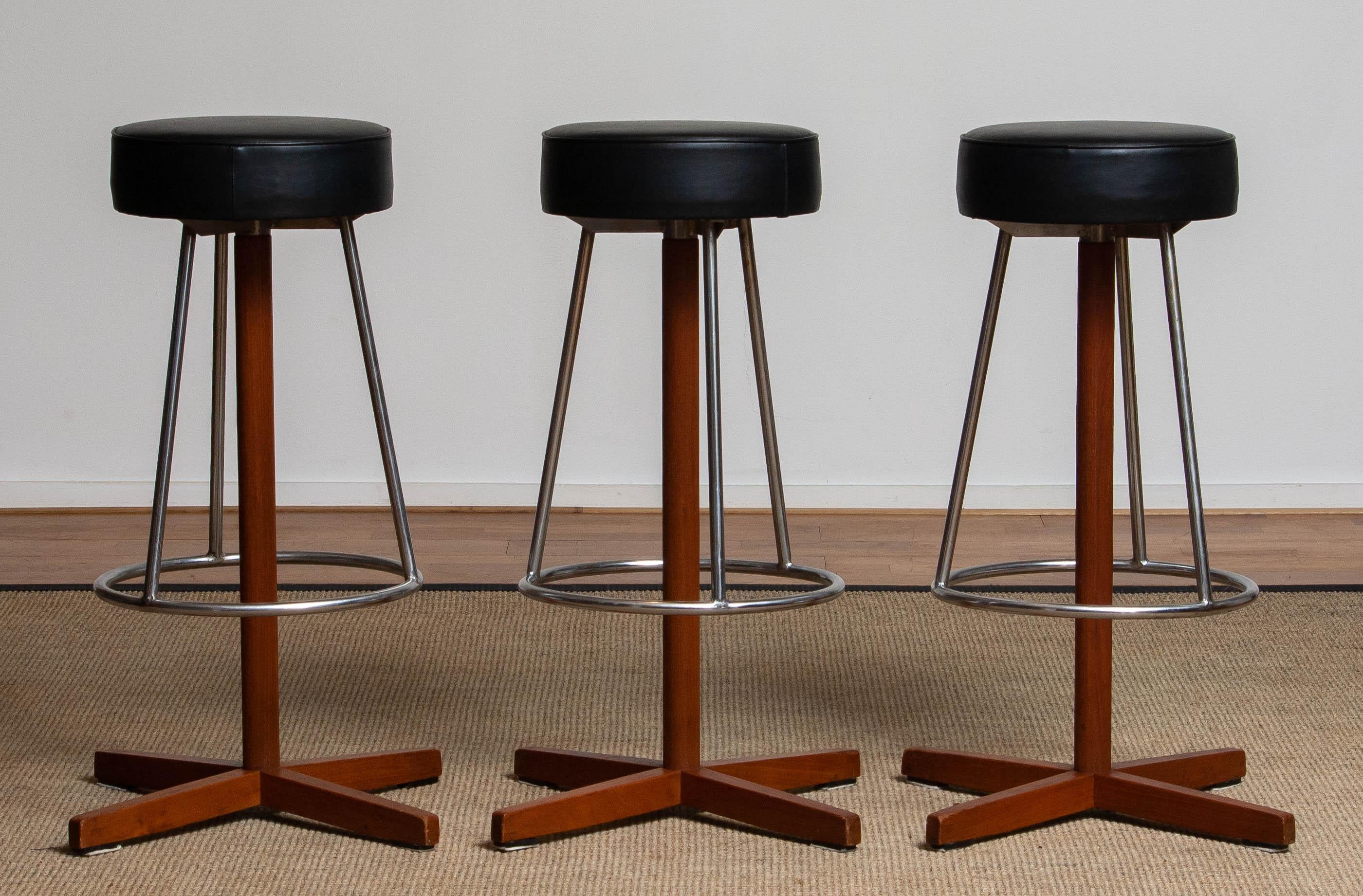 Very beautiful set of three slim teak swivel bar stools by Börje Johanson for Johanson Design Sweden in allover very good condition. All three are upholstered with black faux leather.
