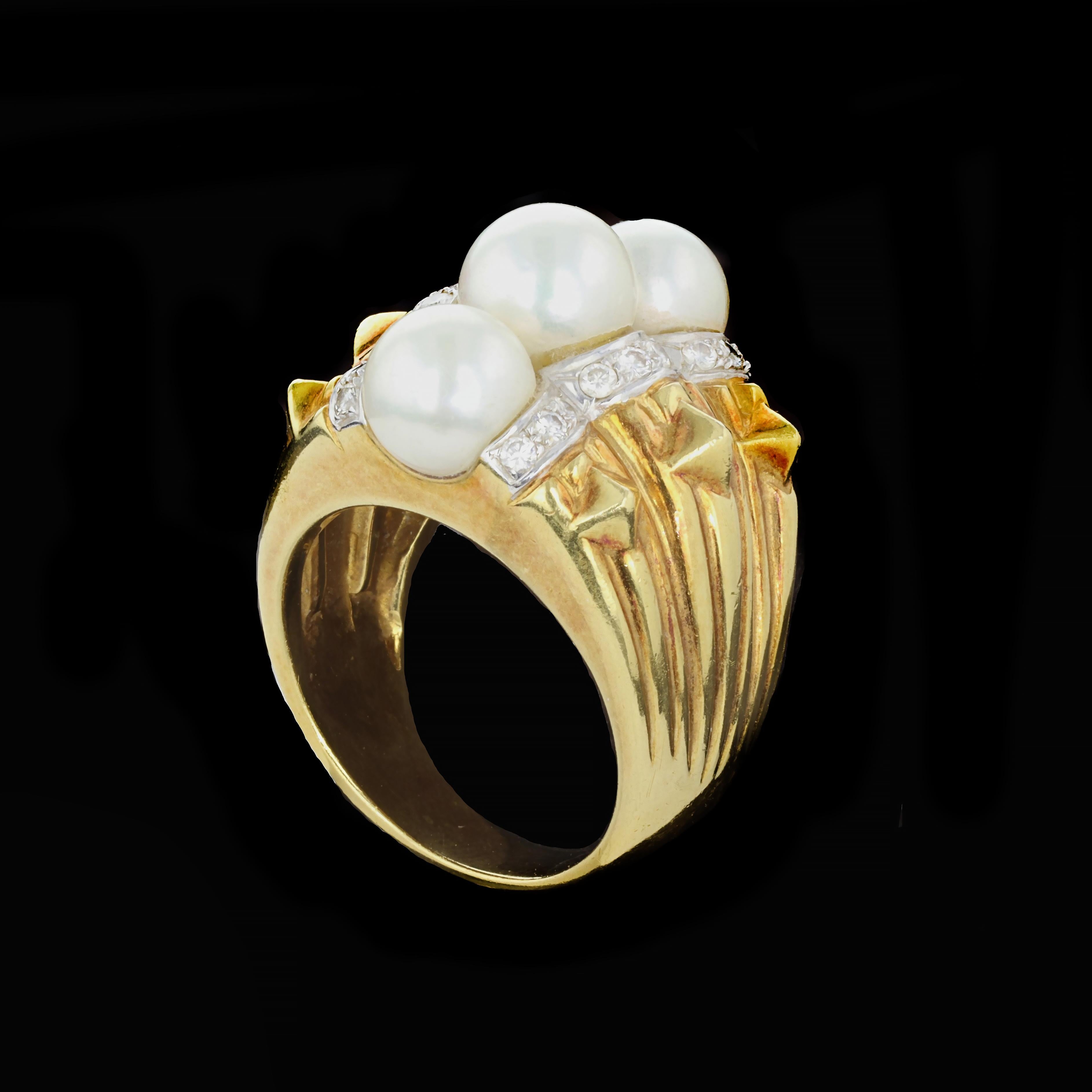 Chic and Stylish, this bold three-dimensional ridge design provides a striking accent and base for the lustrous beauty of three round pearls. The 18K yellow and white gold ring features round white pearls that are accentuated by 18 round cut