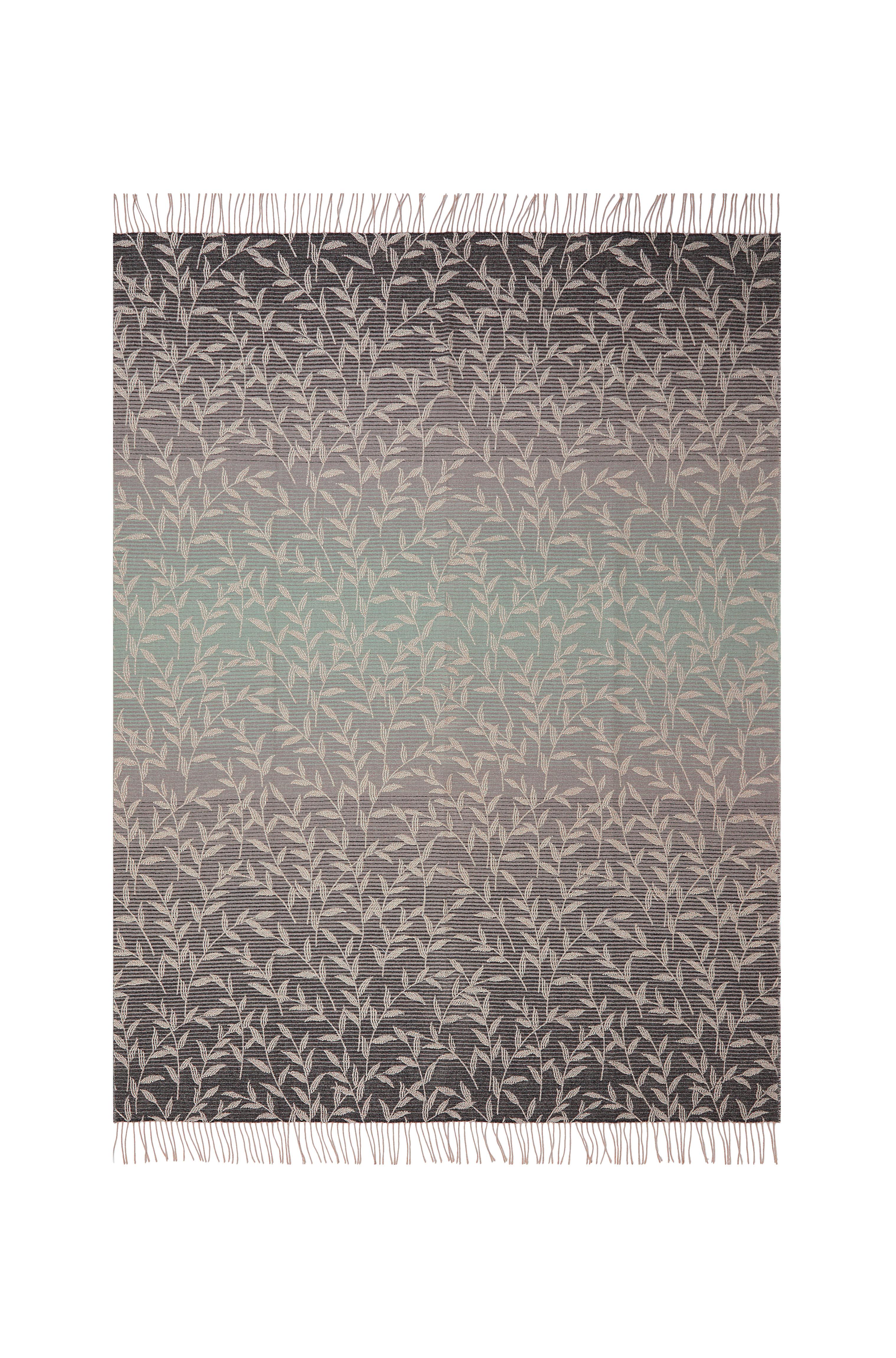 Il s'agit d'un jeté en jacquard dans des tons gris et verts luxuriants, décoré d'un motif de feuilles et terminé par des franges. Le feuillage rappelle la jungle et les éléments naturels caractéristiques de cette collection.