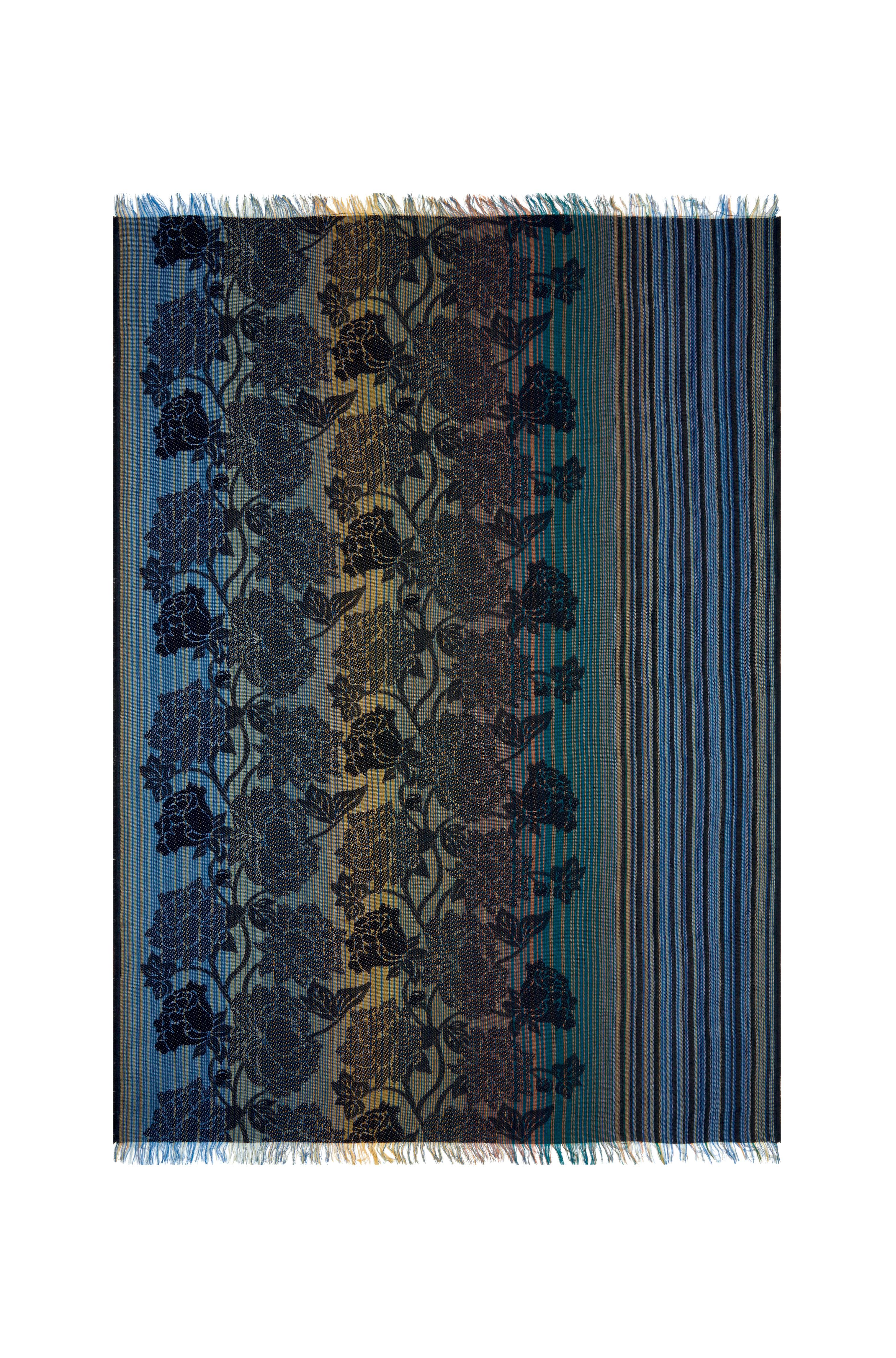Il s'agit d'un jeté en jacquard teint en fil, décoré de rayures bleues, vertes et brunes, avec un motif de fleurs de pivoine et terminé par de courtes franges. Les tons bleus sont caractéristiques de cette collection et confèrent à cette pièce un