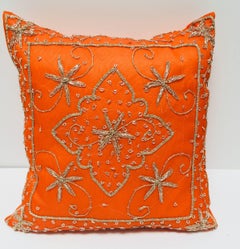 Cojín decorativo naranja adornado con lentejuelas y cuentas