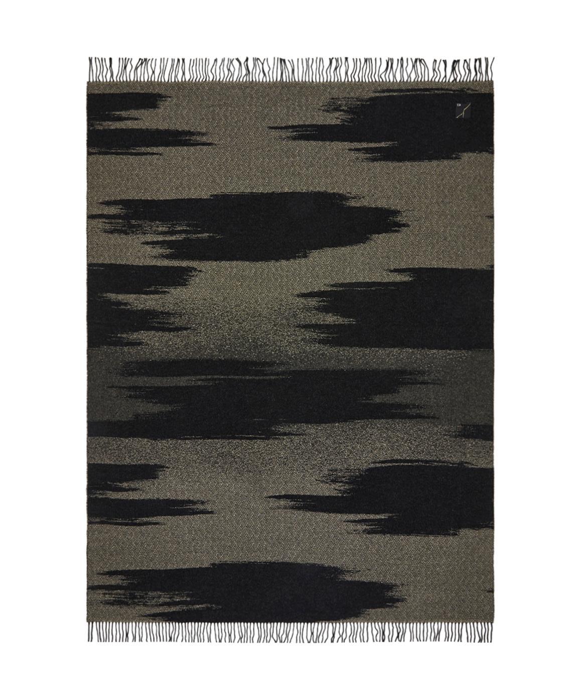 La colección KAMI se compone de mantas de jacquard teñido en hilo con un estampado de grandes nubes doradas, hilos metálicos y flecos cortos. Esta colcha es de un solemne color negro y los diseños de nubes contrastados con el pespunte geométrico