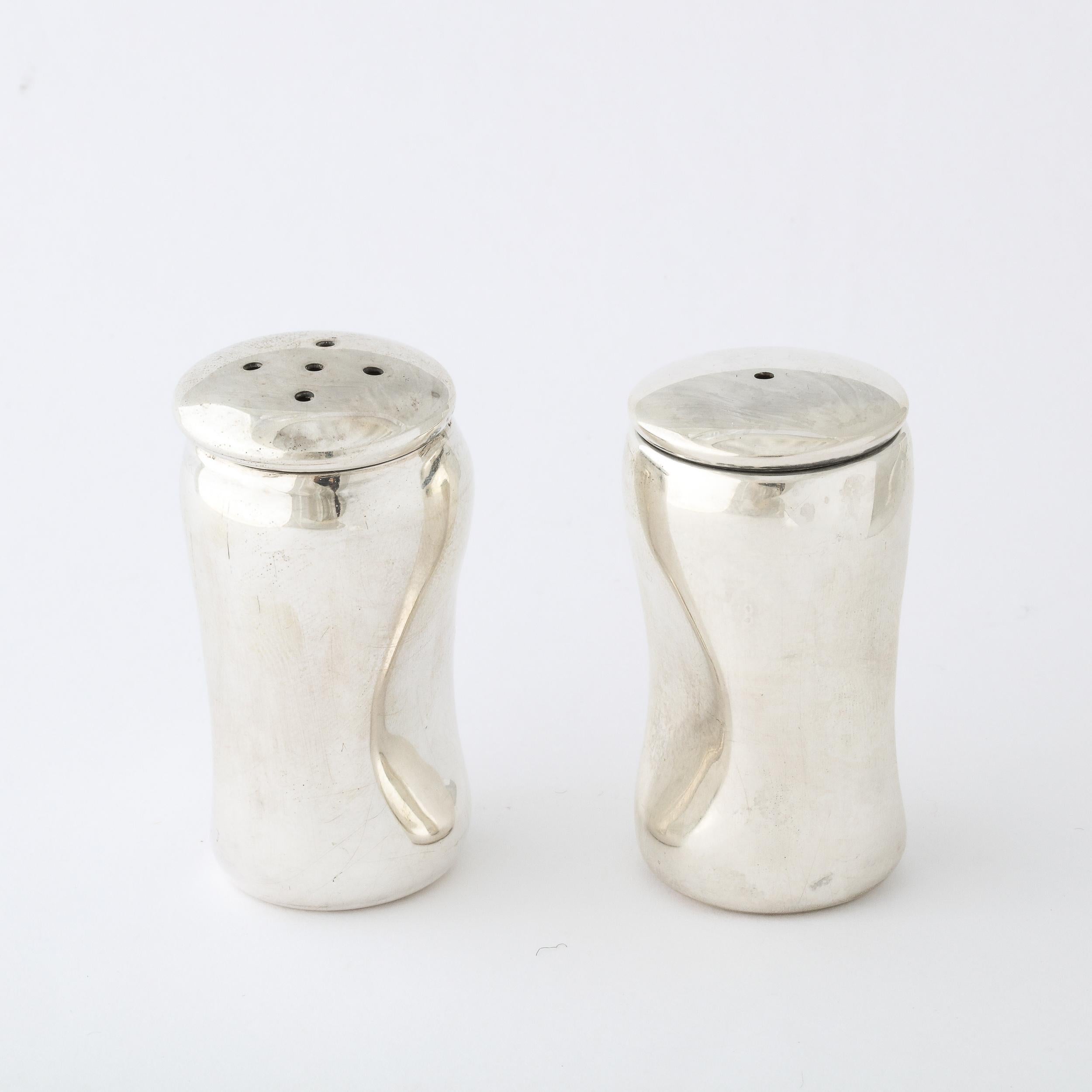 This Pair of Sterling Silver Salt and Pepper Shakers was manufactured by Tiffany and Co. in the United States during the latter half of the 20th Century. Featuring gently tapered forms as though the pieces are holding their breath on a exhalation,