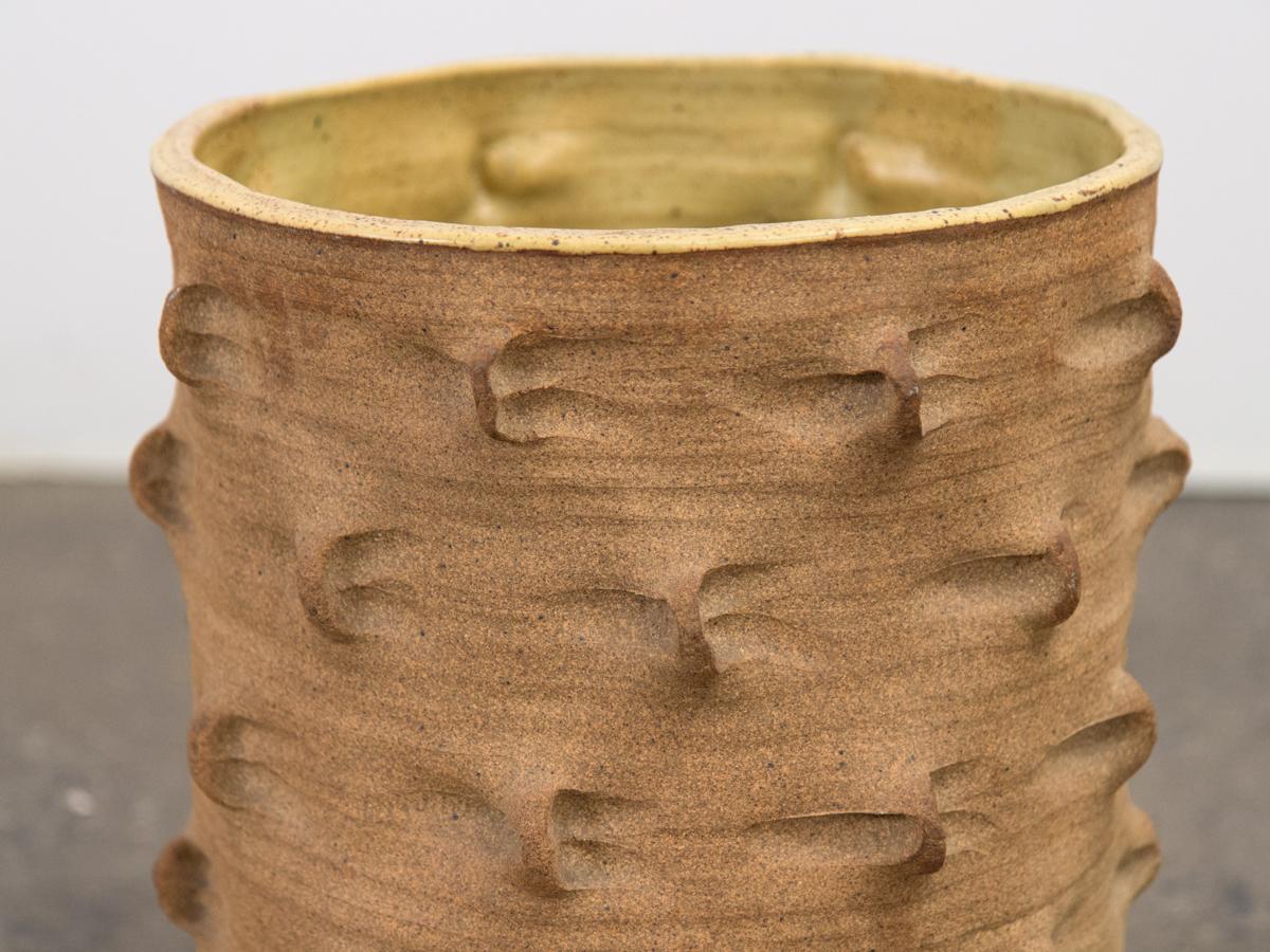 Un pot unique en grès de la céramiste du Studio Marlis Schratter. Ce monumental récipient cylindrique tourné à la roue est orné des stries que l'artiste tire avec son pouce. L'extérieur mat et terreux contraste avec l'intérieur en glacis jaune