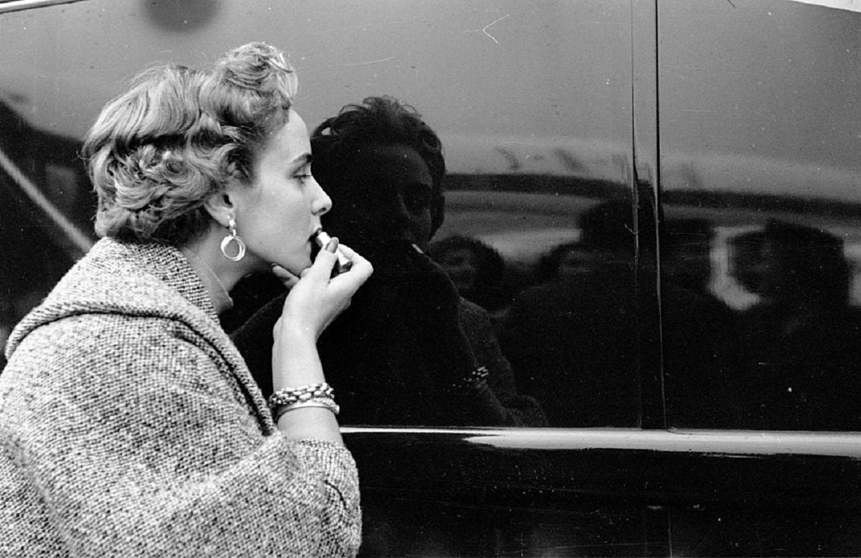 "Lipstick Check" by Thurston Hopkins

7th November 1953: A contestant in a 'Miss World' beauty competition sponsored by Mecca Dancing applying her lipstick using a shiny car as a mirror. Original Publication: Picture Post - 6785 - The Beauty Contest