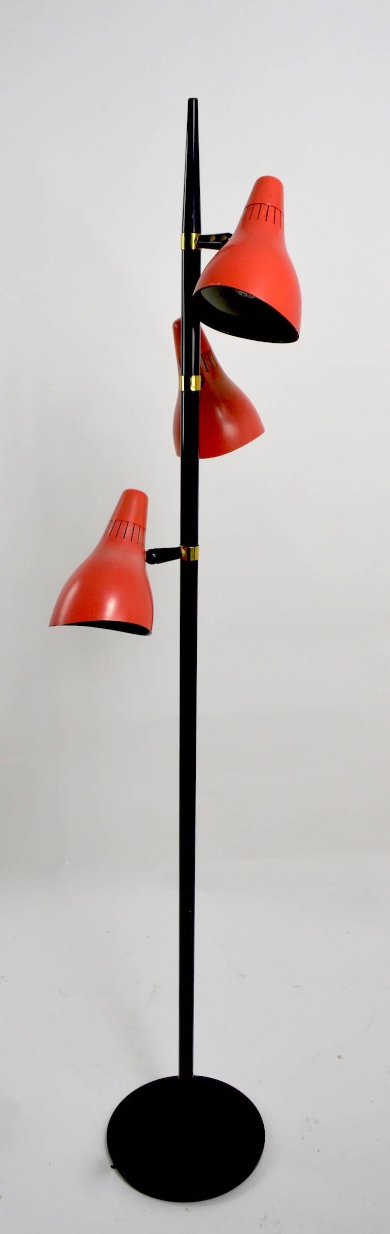 Two three-light floor lamps, designed by Gerald Thurston for Lightolier, each having hooded cone lights ( 8.5 inch L x 5.5 inch Dia. ) which have independent on/off switches, and are adjustable in position. One floor lamp has three different colored