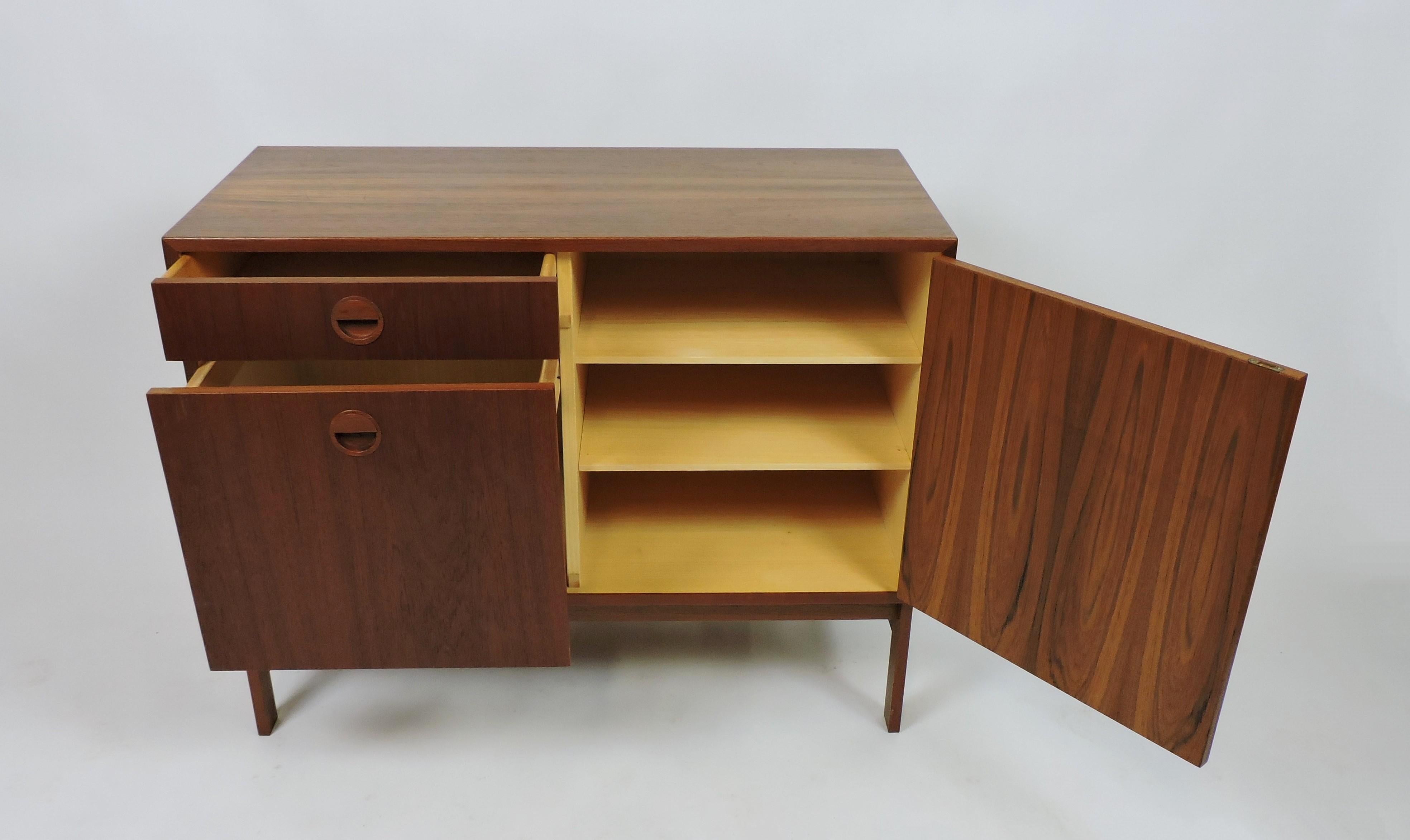 Handsome teak cabinet designed by Rud Thygesen and Johnny Sorensen and made in Denmark by Hansen and Guldborg. This cabinet has one drawer, a compartment with two adjustable shelves, and a filing cabinet, all with the distinctive circular pulls of