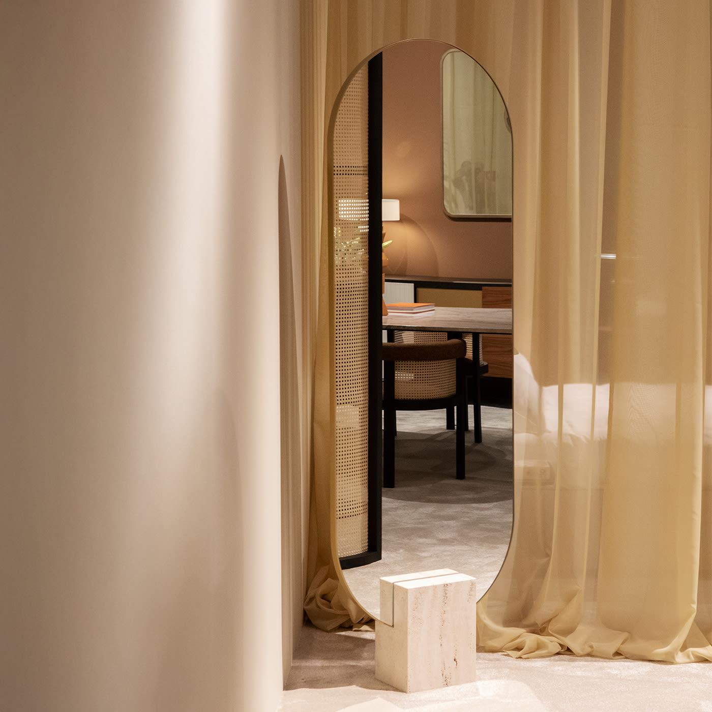Minimalist volumes and precious sartorial details combine to lend this modern freestanding mirror its glamorous allure. Fitted to a bold open-pore Travertine block serving as a sculptural base, the extra-clear mirrored glass—defined by rounded