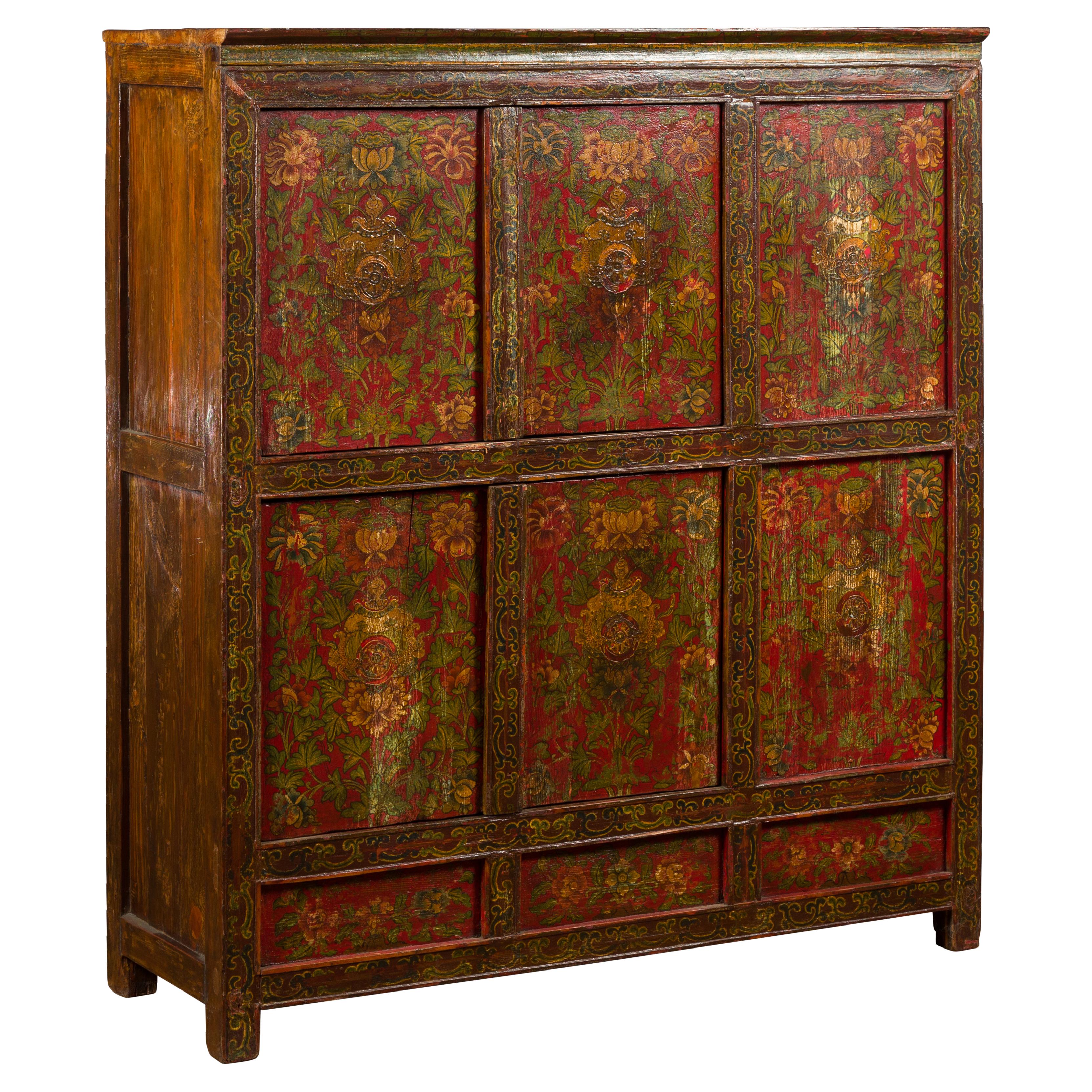 A Tibetan hand-painted cabinet from the 19th century, with two pairs of doors and floral motifs. Created in Tibet during the 19th century, this cabinet captures our attention with its clean lines and abundant hand-painted yellow and green floral