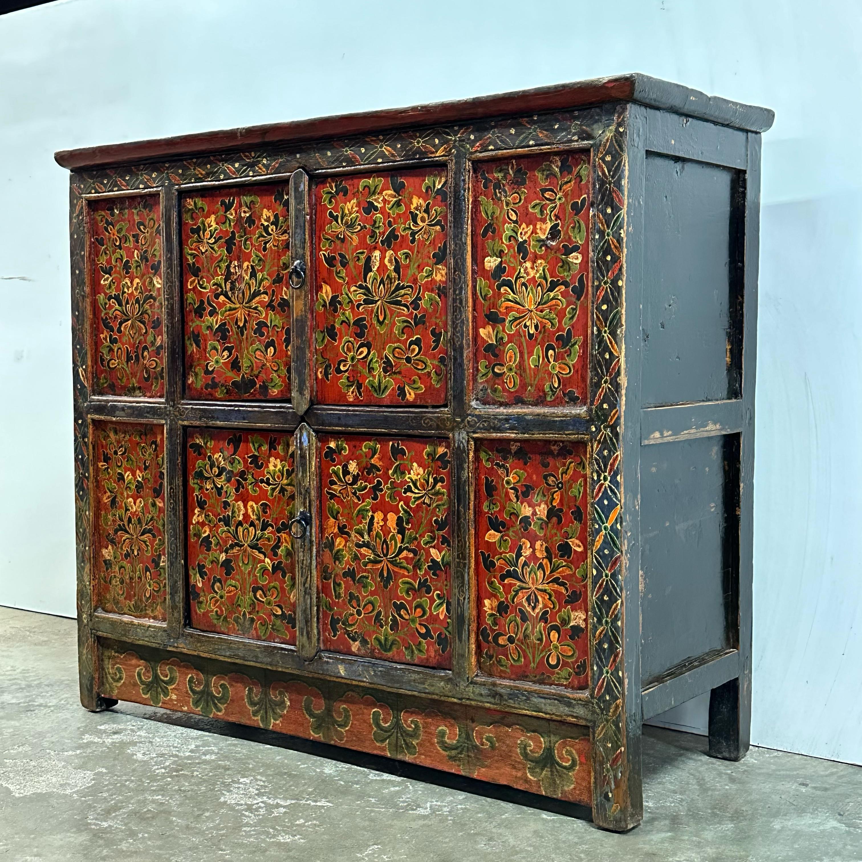 A striking Tibetan cabinet dating to the late 19th century, featuring its original hand-painted floral motifs in hues of green, white, and black. This beautiful colour palette lends the piece a subtle yet captivating presence. Below, graceful cloud