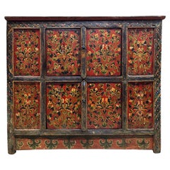 Armario tibetano del siglo XIX con diseño floral pintado a mano sobre fondo rojo
