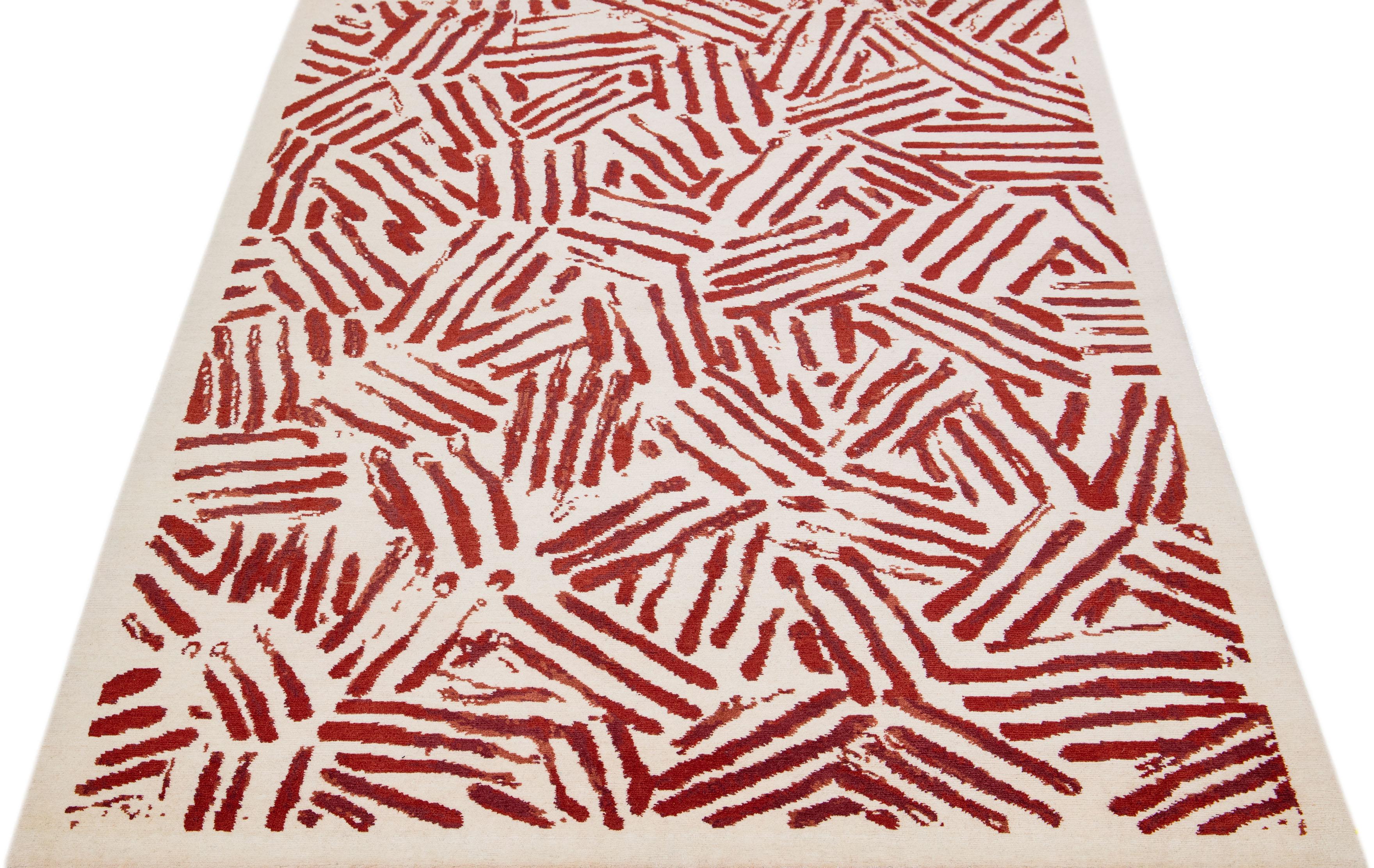 Dieser atemberaubende, moderne tibetische Wollteppich zeichnet sich durch aufwendige, handgeknüpfte Kunstfertigkeit aus, mit einem beigen Grundton und einem raffinierten, geometrischen Muster, das durch geschmackvolle rote Akzente ergänzt