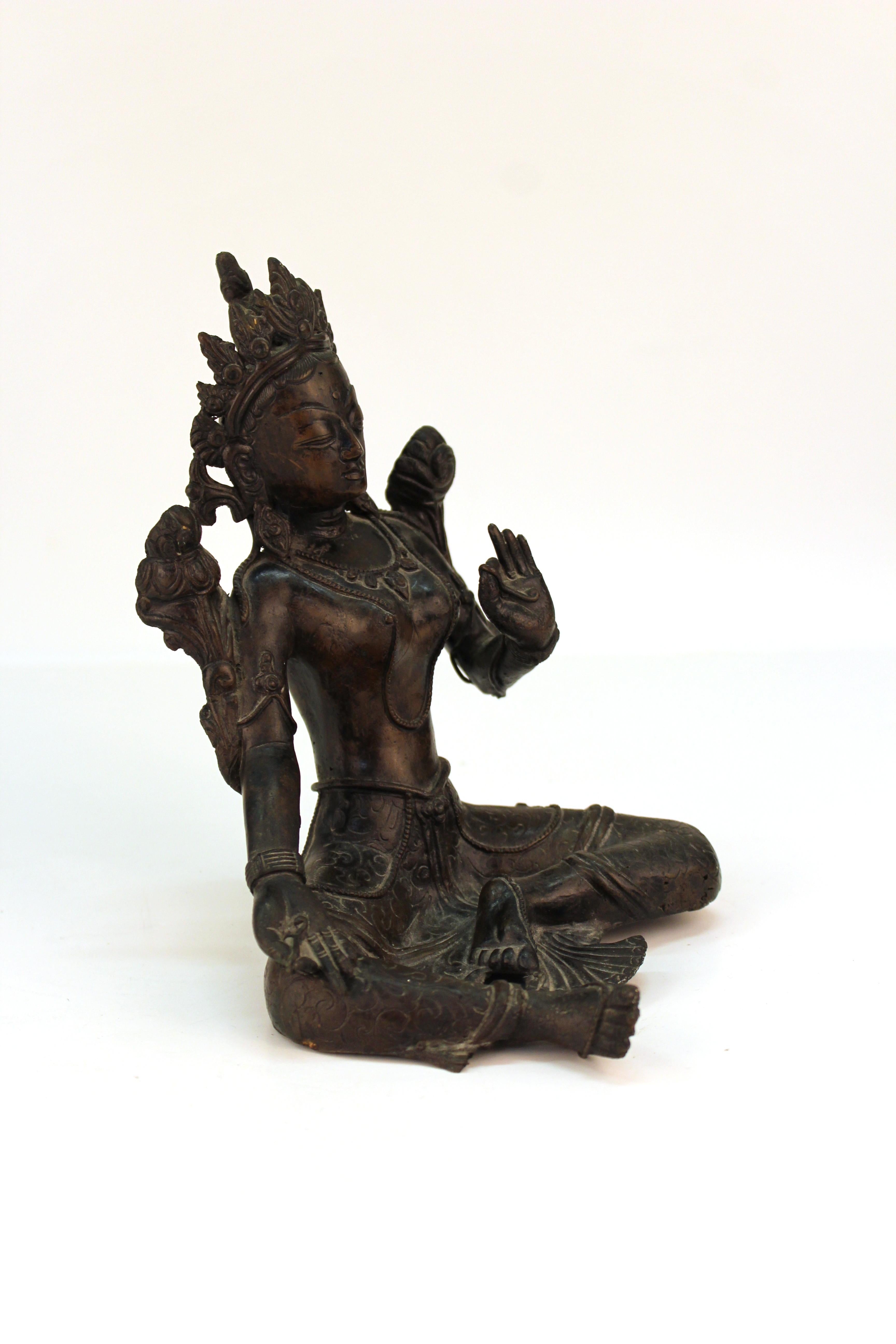 Tibetan bronzed metal Himalayan Buddhist sculpture depicting the seated Bodhisattva Tara in position of Abhaya mudra. The piece is in great vintage condition and has age-appropriate patina and wear.