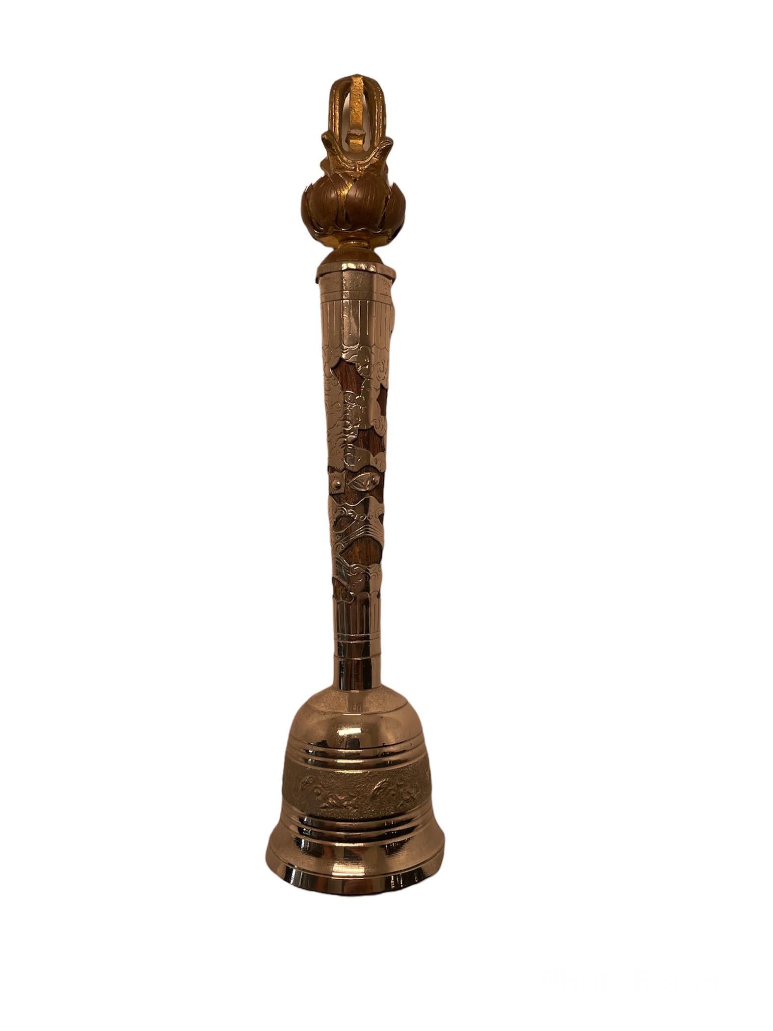This is a Tibetan Buddhism silver overlay and wood bell. The bell metal body as well of the silver overlay handle is engraved with flowers. The top of the handle is decorated with a finial made of Lotus flowers and a crown. The Lotus flower
