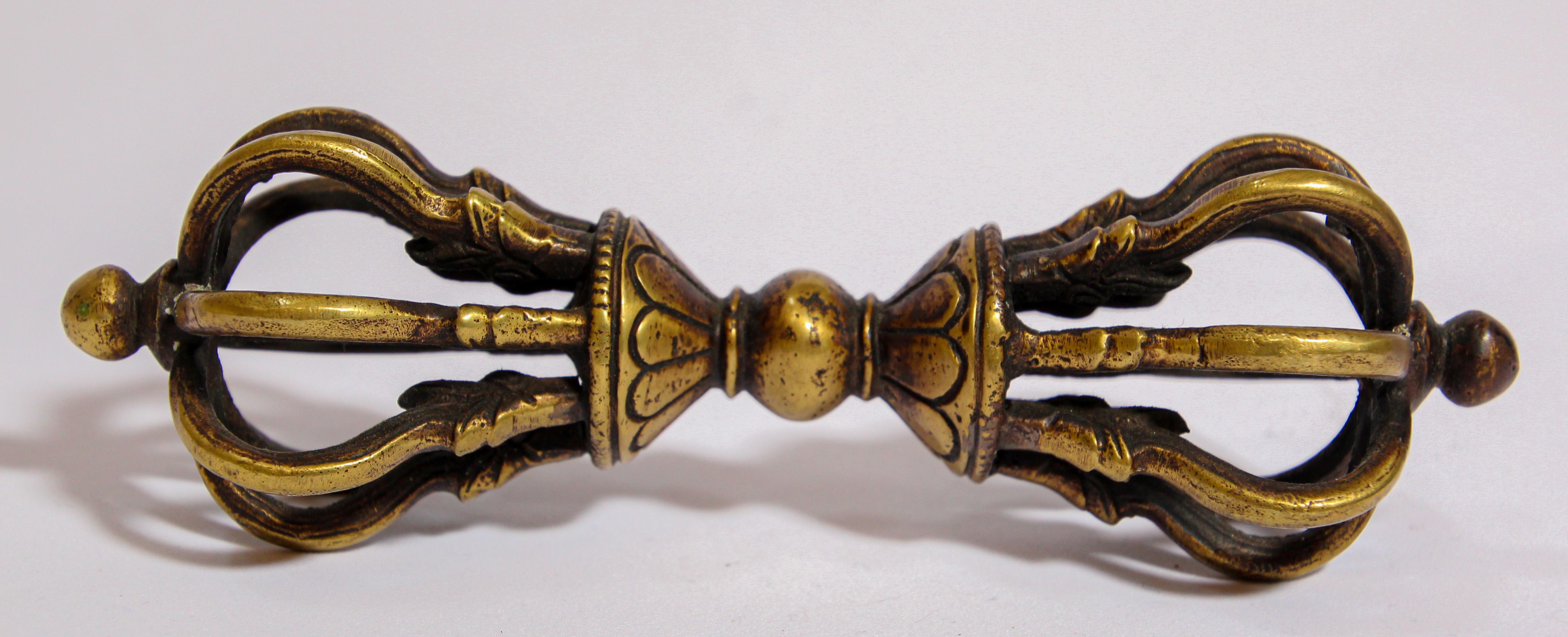 A Tibetan Buddhist gilded cast bronze Vajra
The gilt bronze Vajra thunderbolt-scepter is cast with a central bulbous grip that separates two lotus pedestals supporting a central column surrounded by eight arched vajra points emerging from the jaws