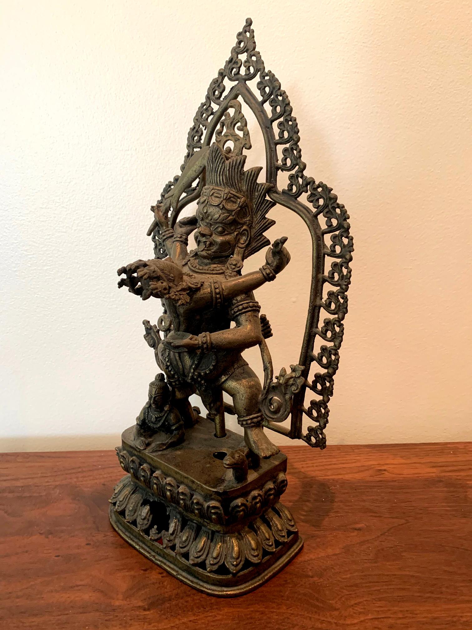 A cast bronze statue of Yamantaka and his envisioned consort Vajravetali on lotus throne and with a halo canopy, Tibetan, circa 19th century. The statue was cast in section with the main figures inserted onto the throne. Yamantaka, also known as